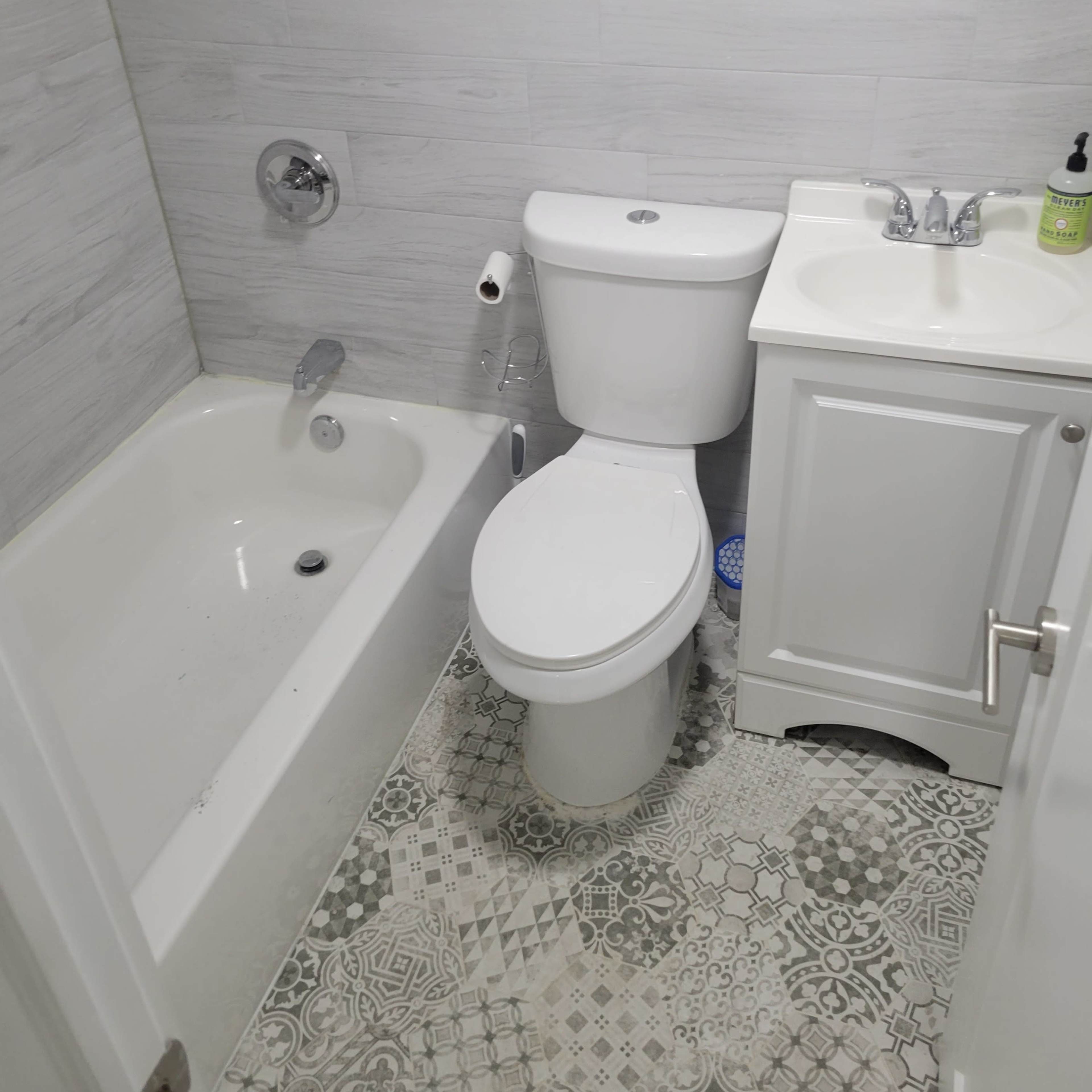 A small bathroom featuring a bathtub, toilet, and sink with a cabinet beneath.