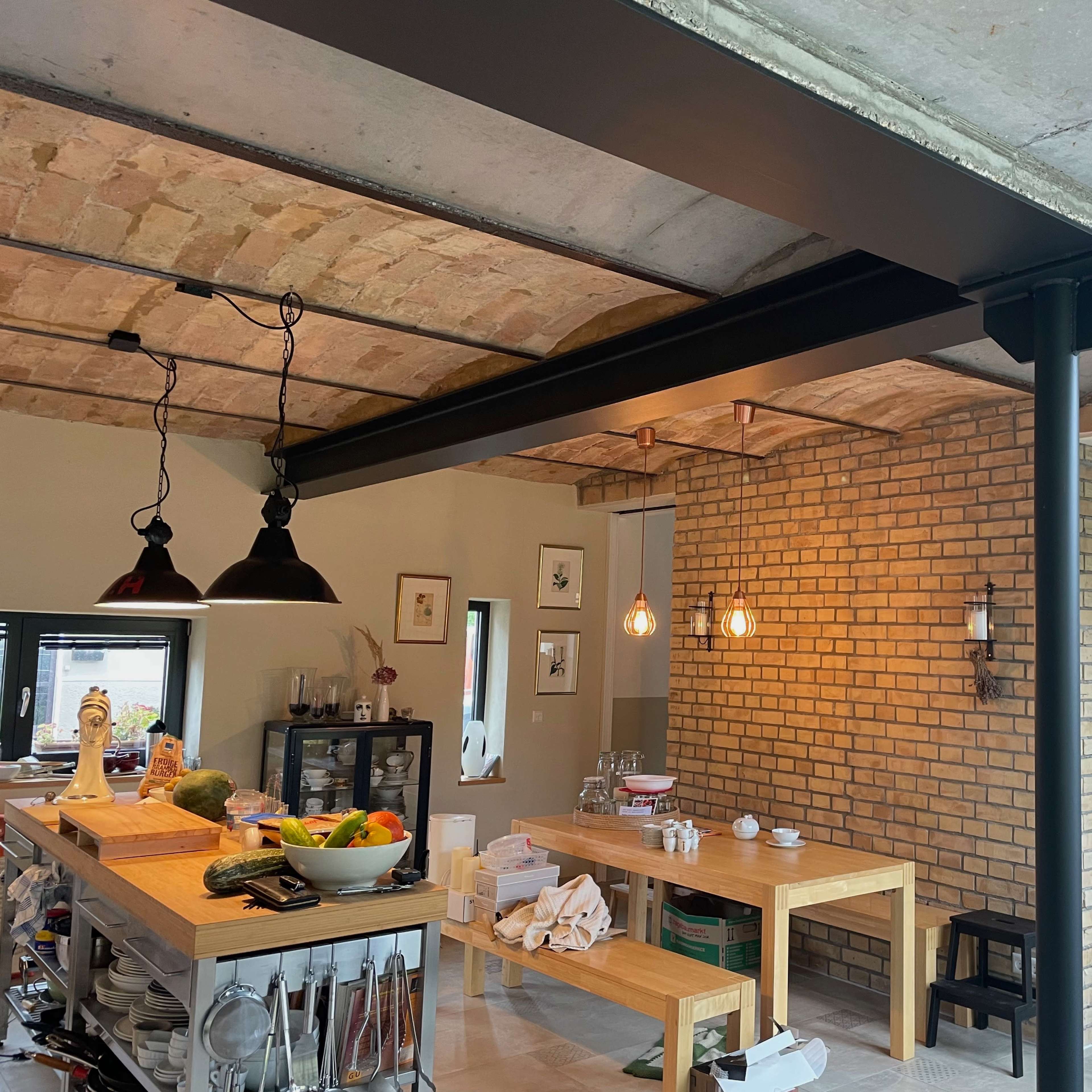A modern kitchen with exposed brick walls, wooden tables, and industrial-style lighting.