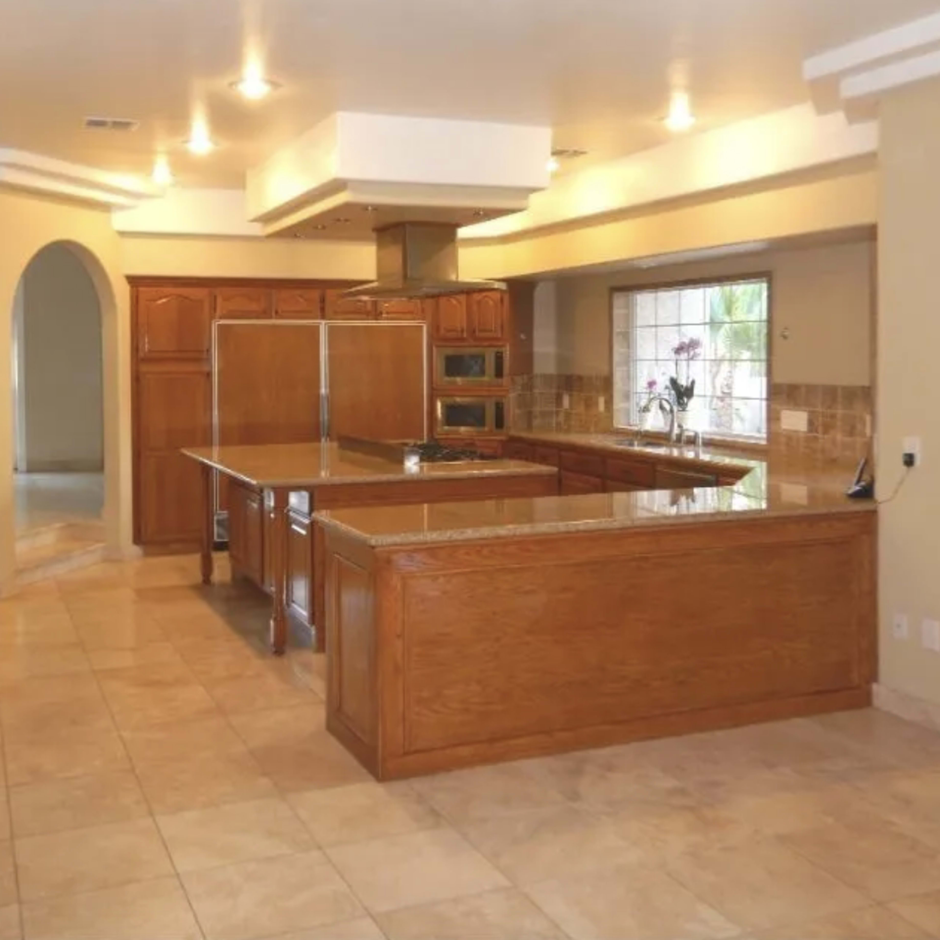 A spacious kitchen featuring wooden cabinets, granite countertops, and modern appliances.
