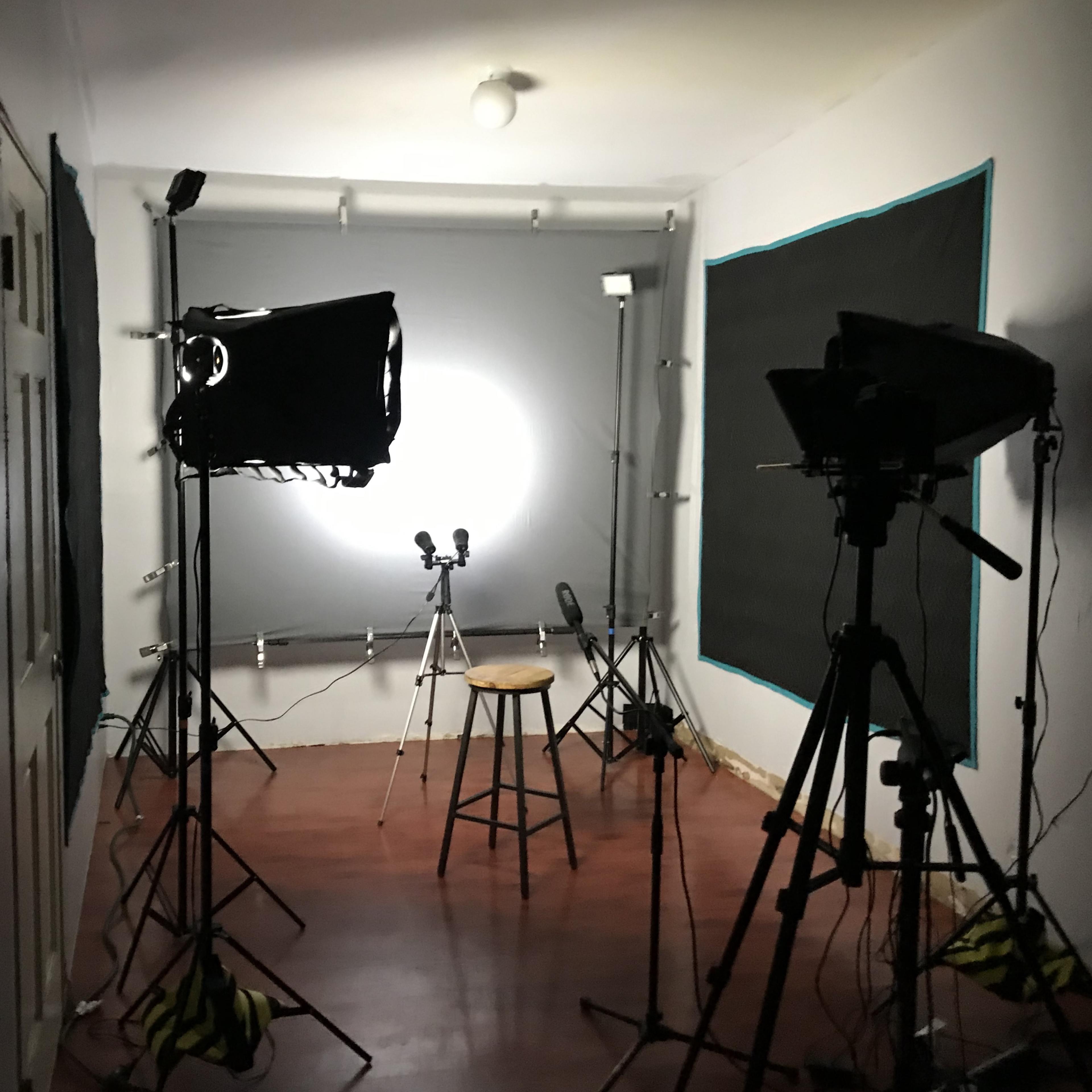 A photography studio with multiple lighting setups, a stool in the center, and a backdrop.