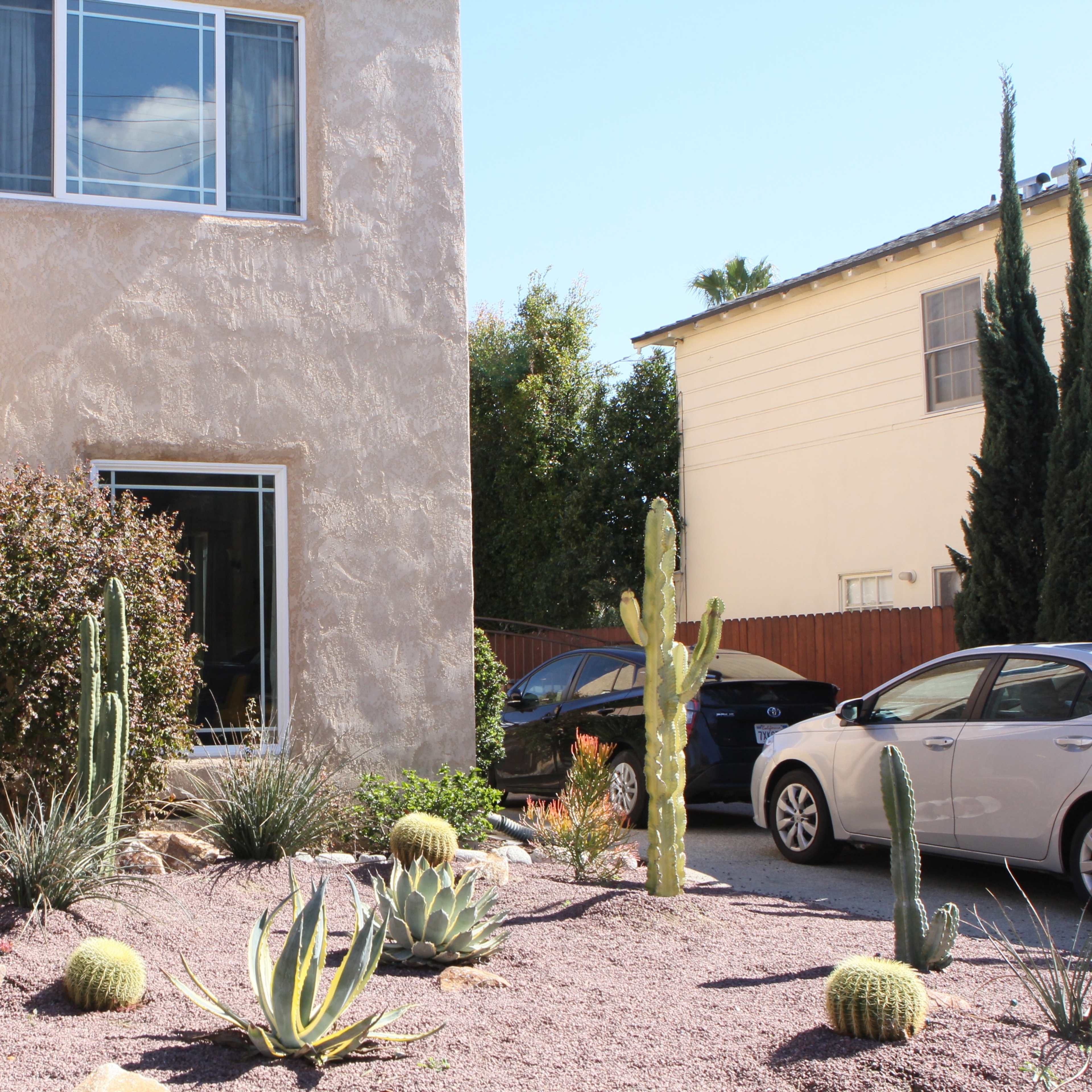 A house with a stucco exterior, featuring a landscaped front yard with various cacti and succulents on gravel.