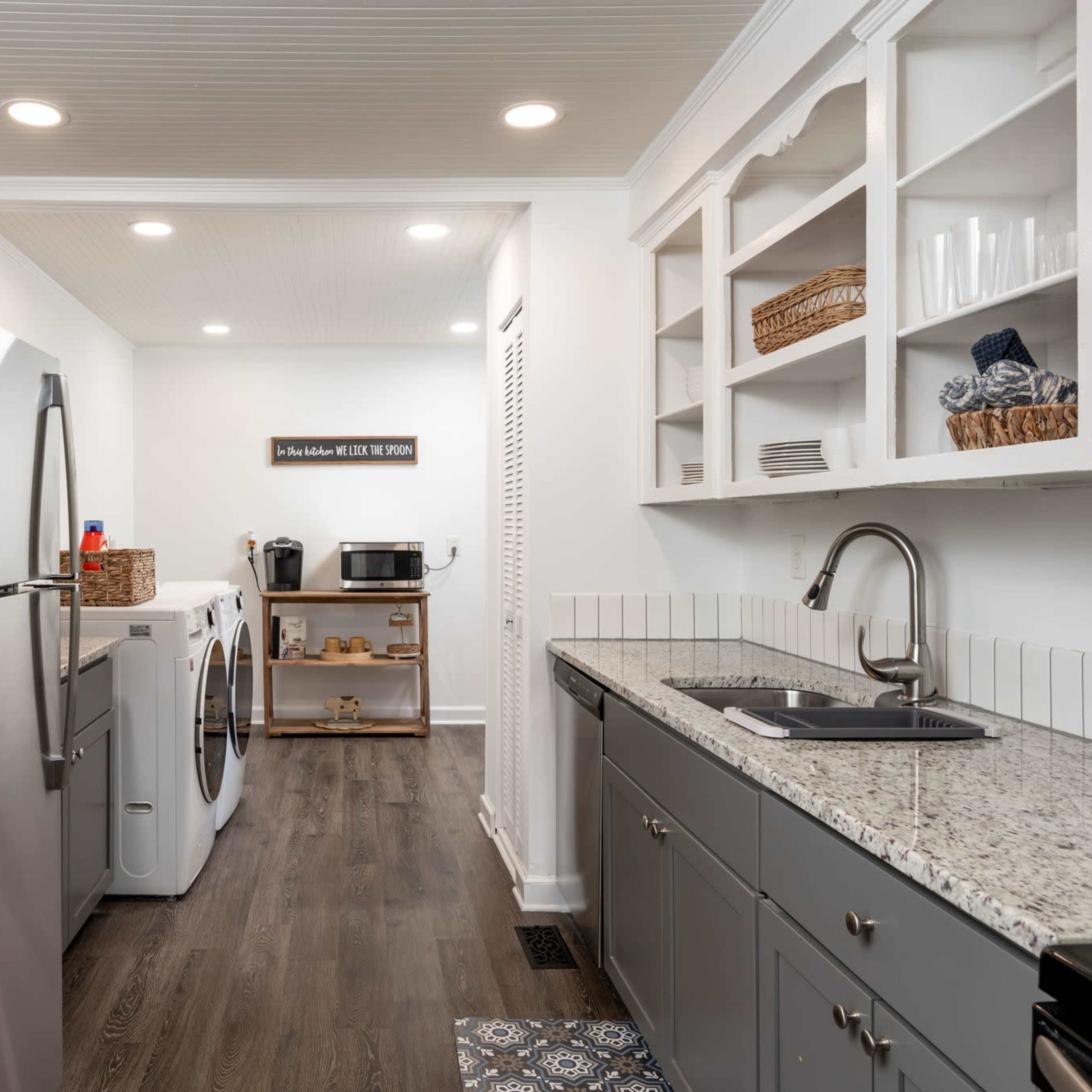 A modern kitchen features stainless steel appliances, granite countertops, and a laundry area with washer and dryer.