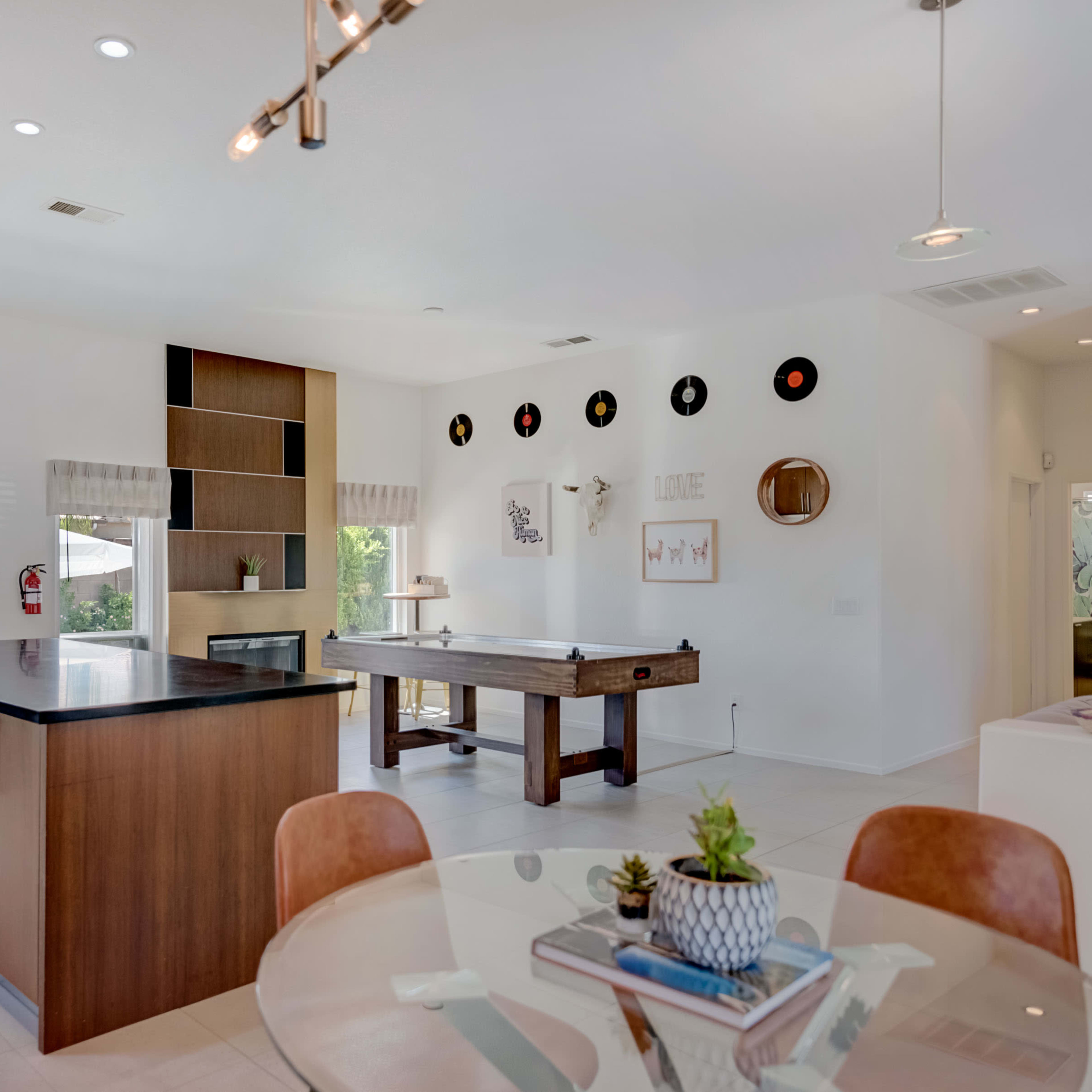 A modern kitchen and dining area feature a large island, a dining table, and a pool table, with sliding glass doors leading to an outdoor patio.