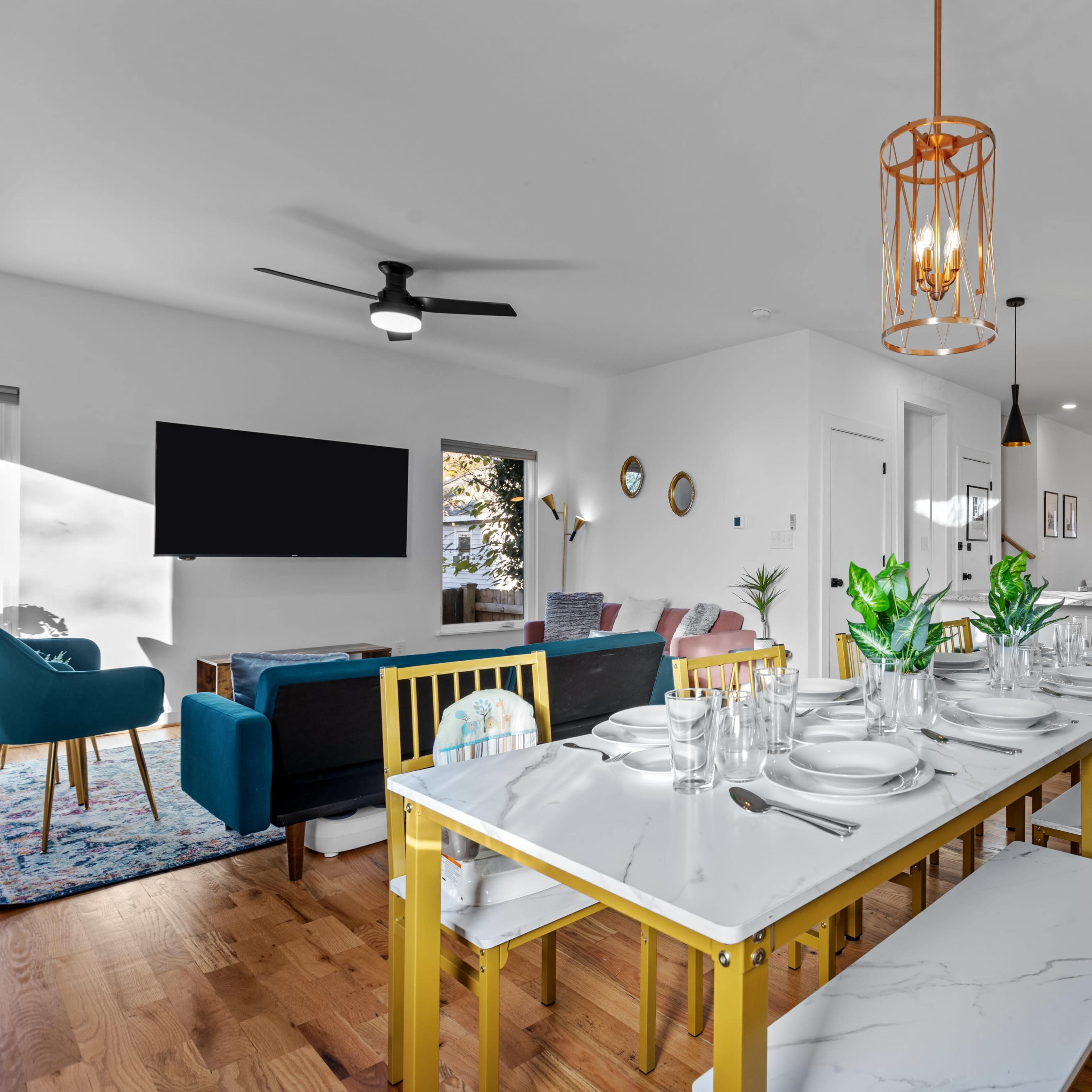 A modern dining room features a marble table set for dinner, surrounded by stylish chairs, with a living area visible through an open space.