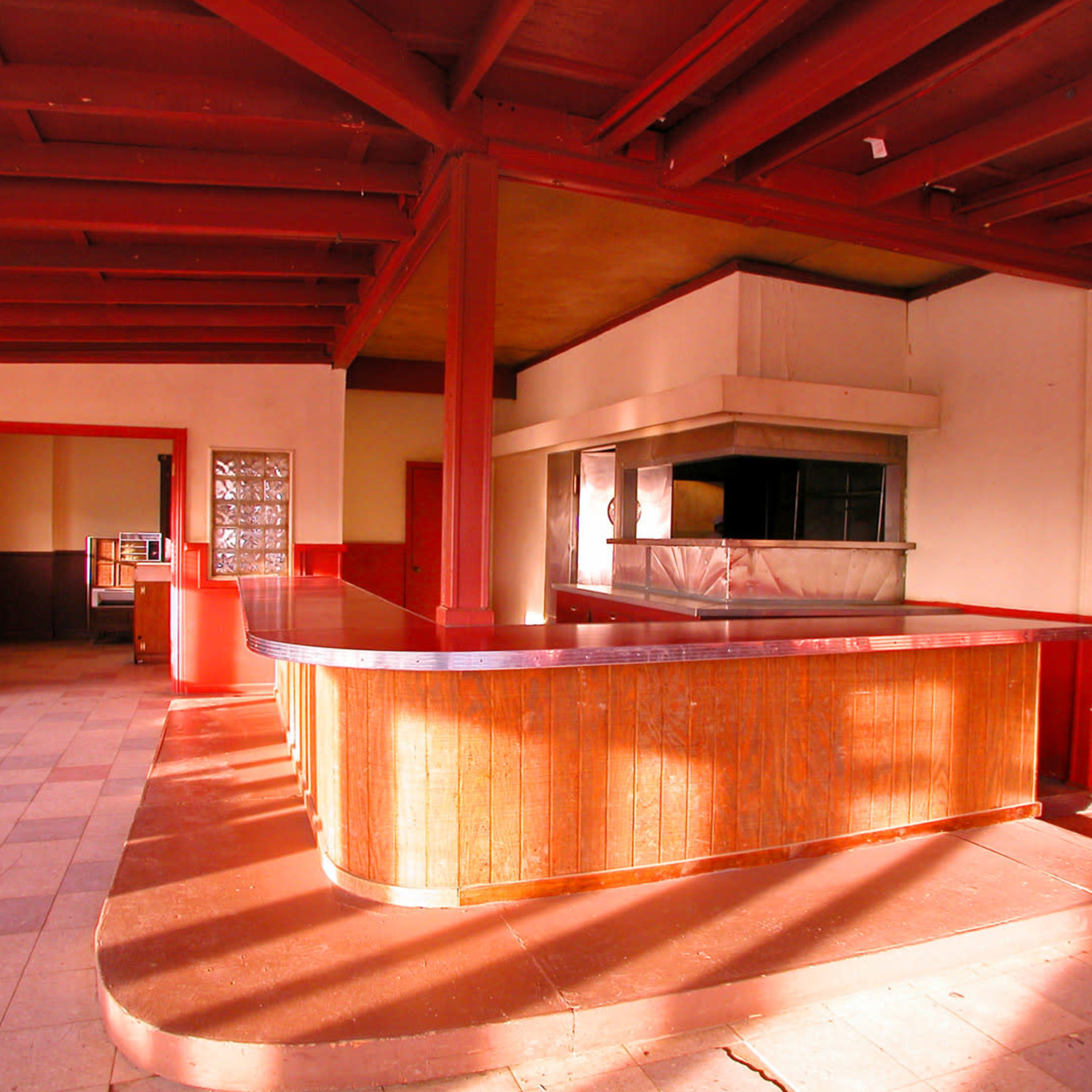 An empty, well-lit interior of a building featuring a wooden counter and red walls.
