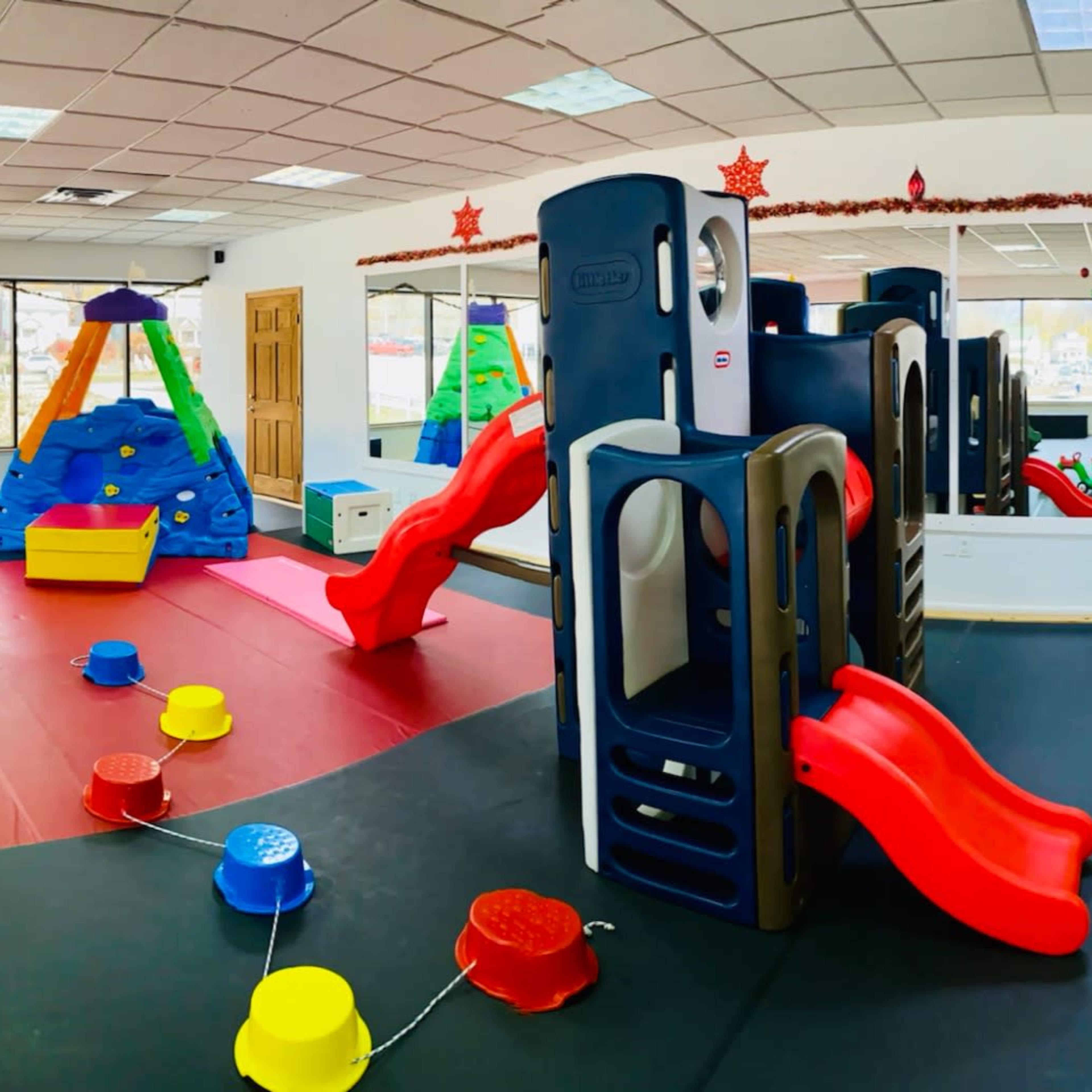 A colorful indoor play area filled with various play structures, toys, and slides.