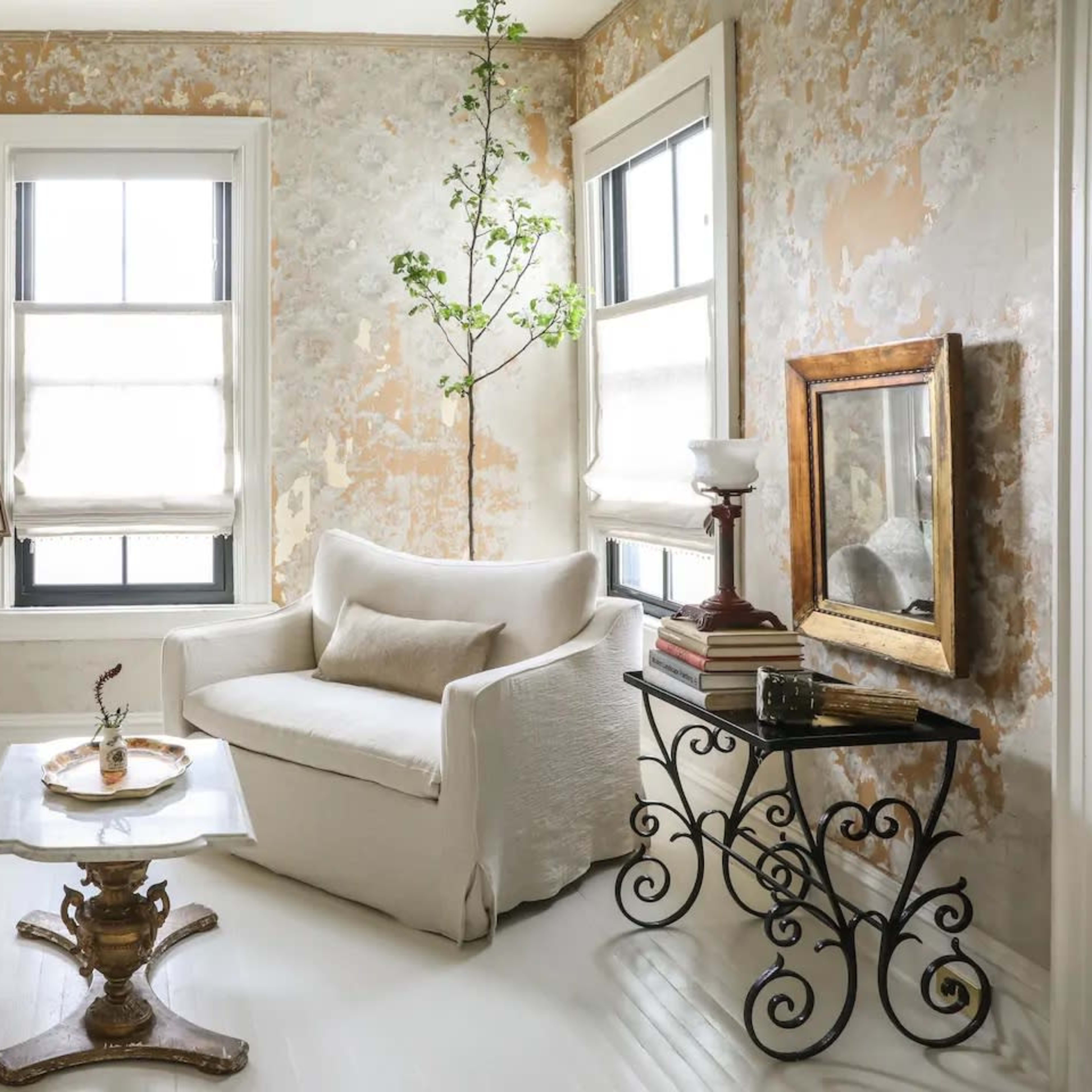 A living room with two sofas, a coffee table, a small plant, and walls adorned with textured wallpaper.