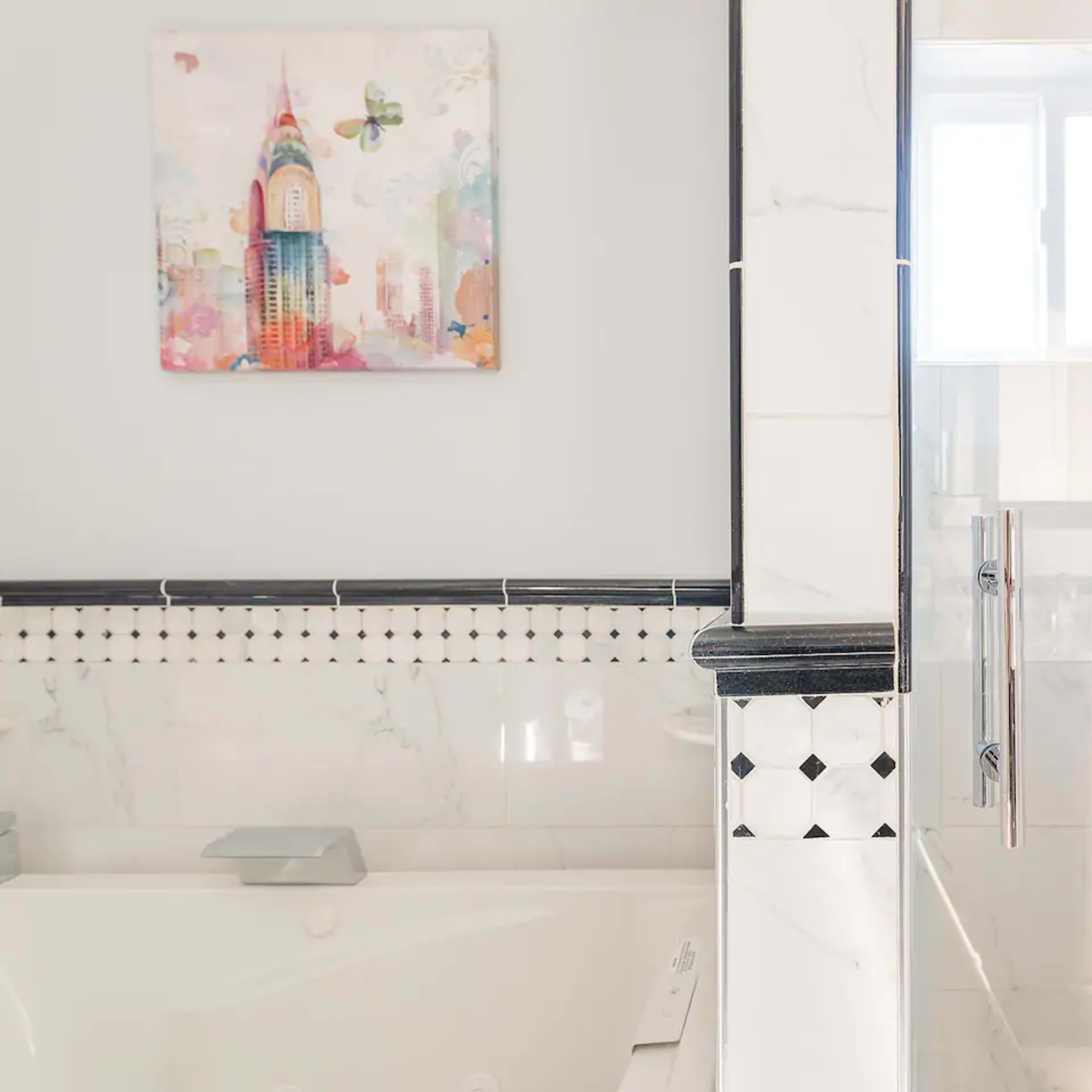A modern bathroom featuring a bathtub, a walk-in shower with a glass door, and a colorful artwork of a skyscraper on the wall.