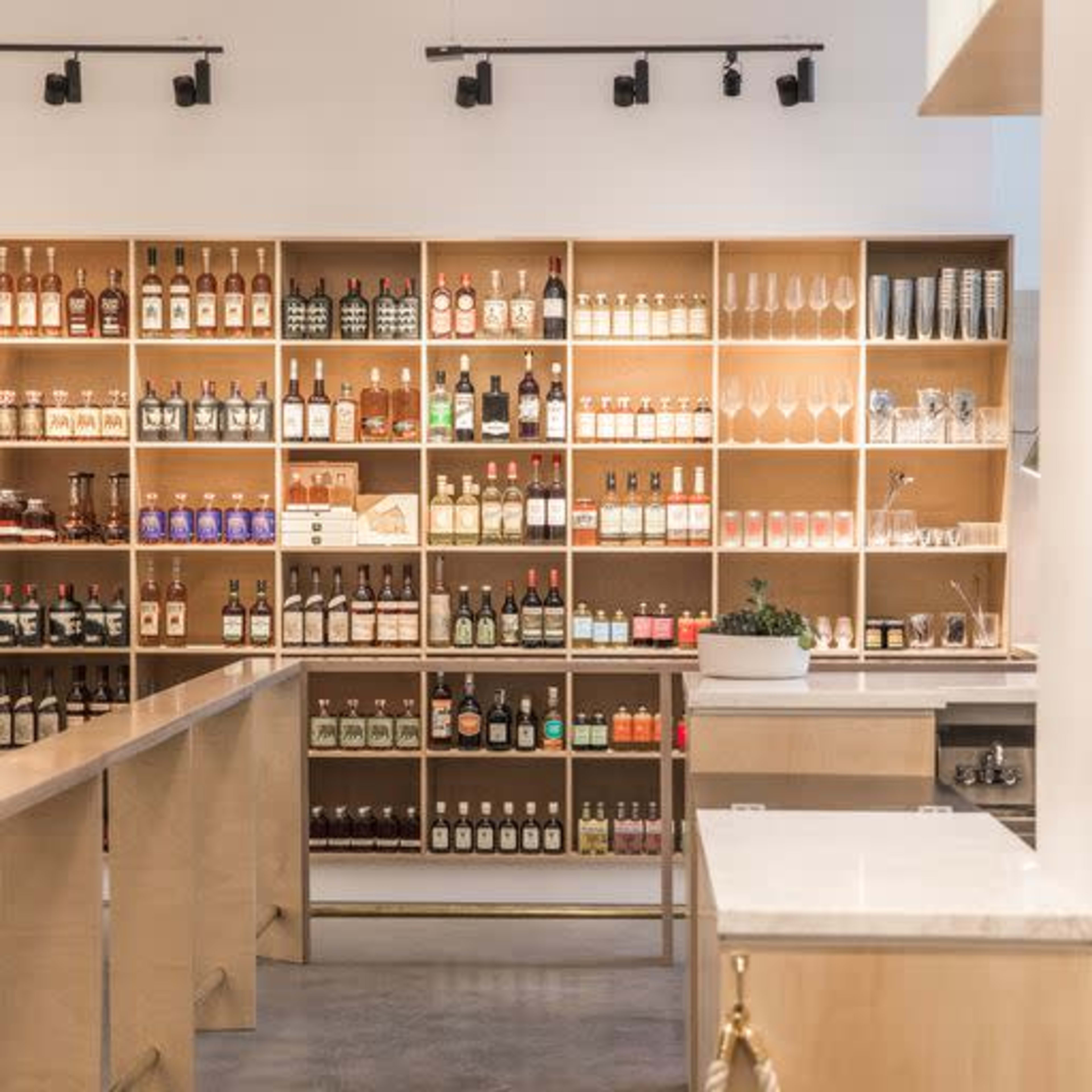 A well-organized bar shelf stocked with various bottles of liquor and glassware in a modern setting.