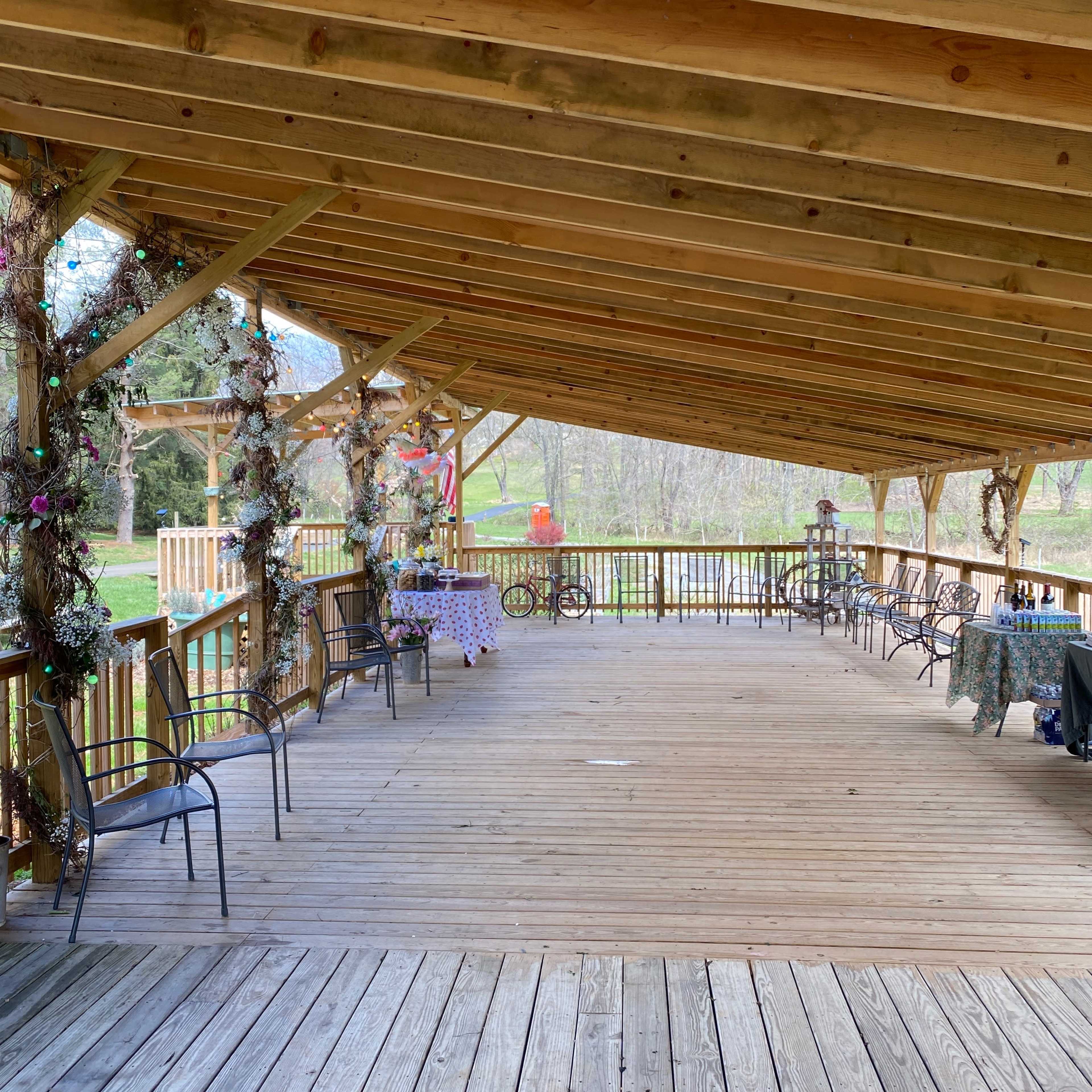 A spacious wooden deck with a slanted roof, featuring several chairs and decorative elements along the railing.