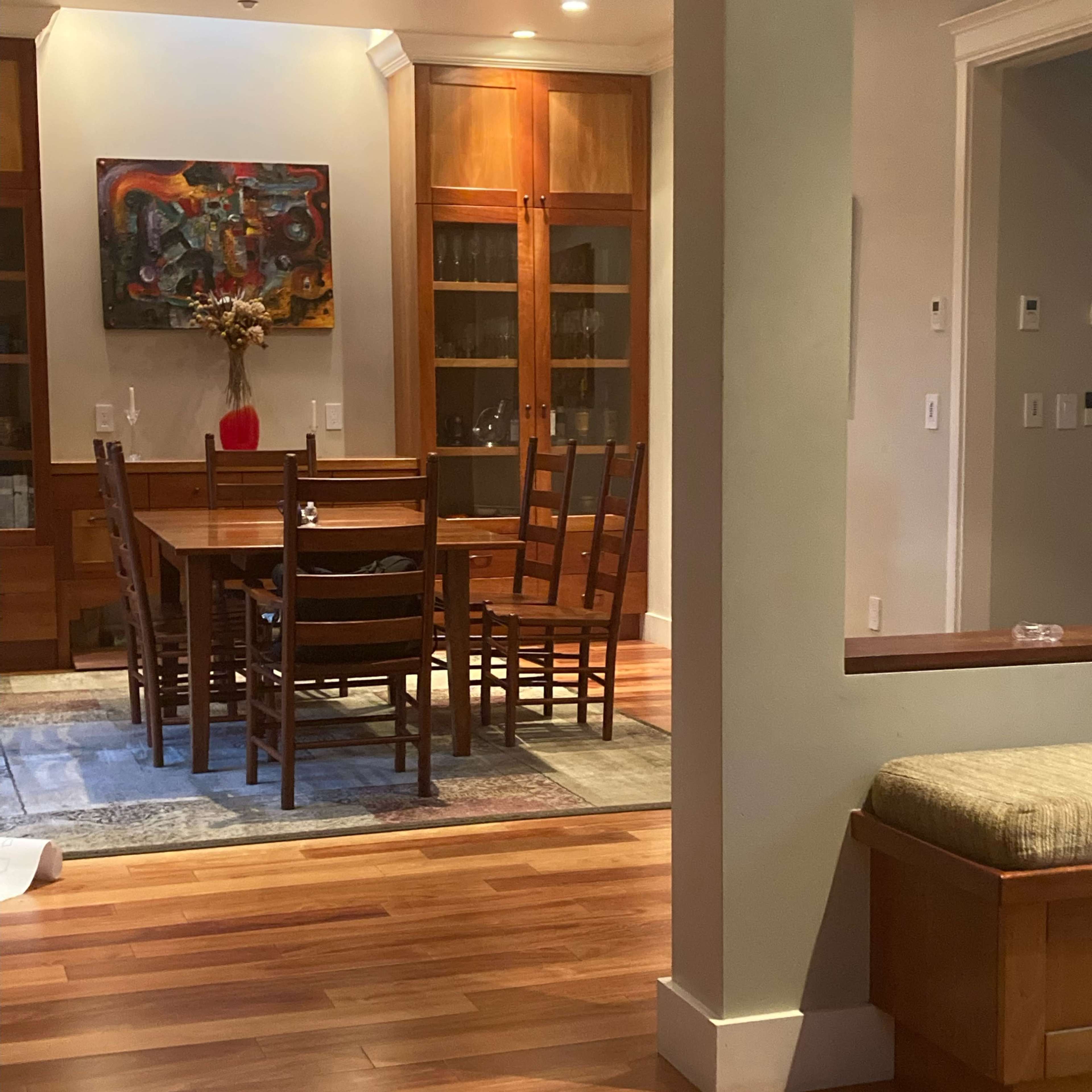 A dining area with a wooden table and chairs, surrounded by glass-front cabinets, and a decorative piece on a side table.