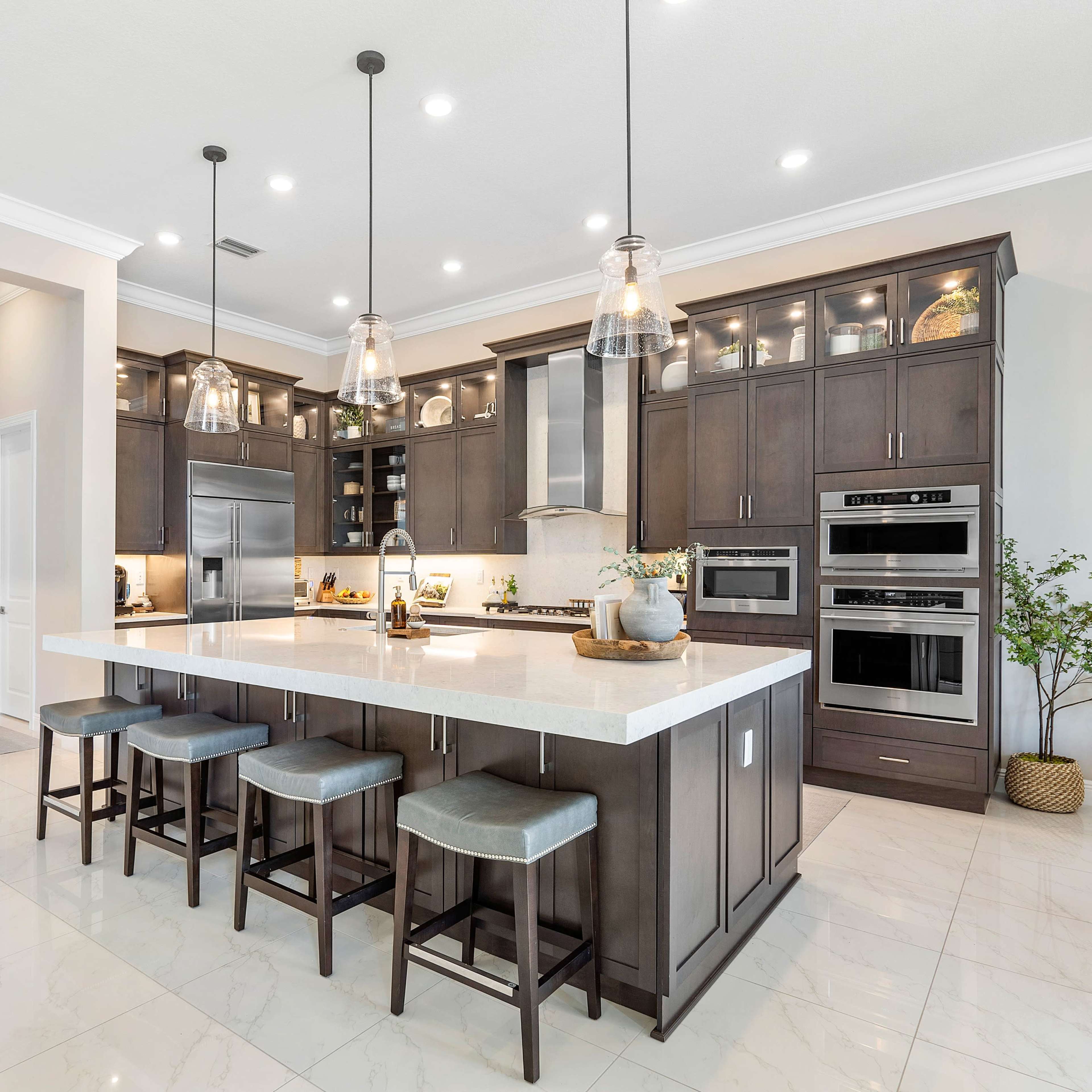 A modern kitchen features dark cabinetry, stainless steel appliances, and a large central island with four stools.