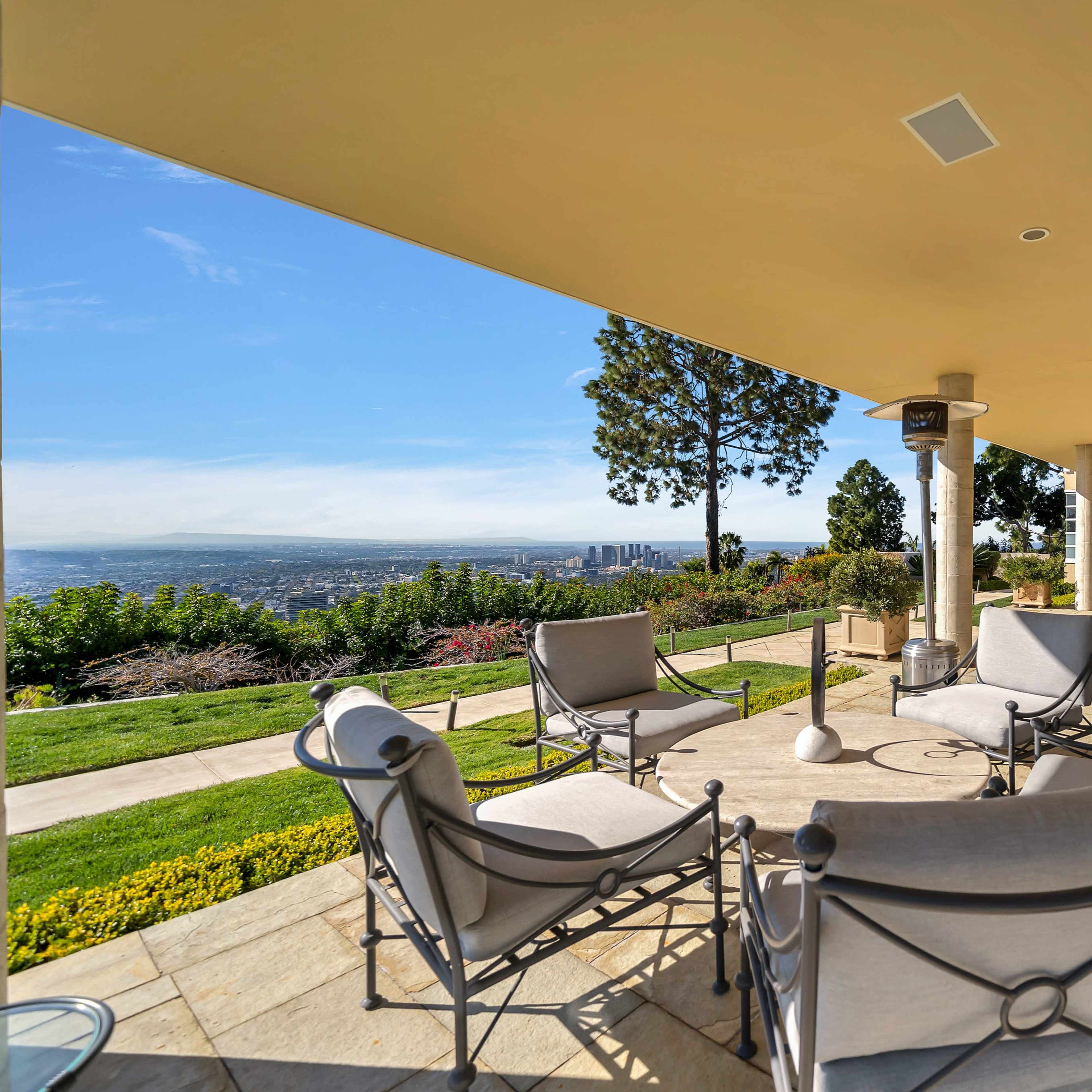 A patio with several chairs overlooks a cityscape and lush greenery.