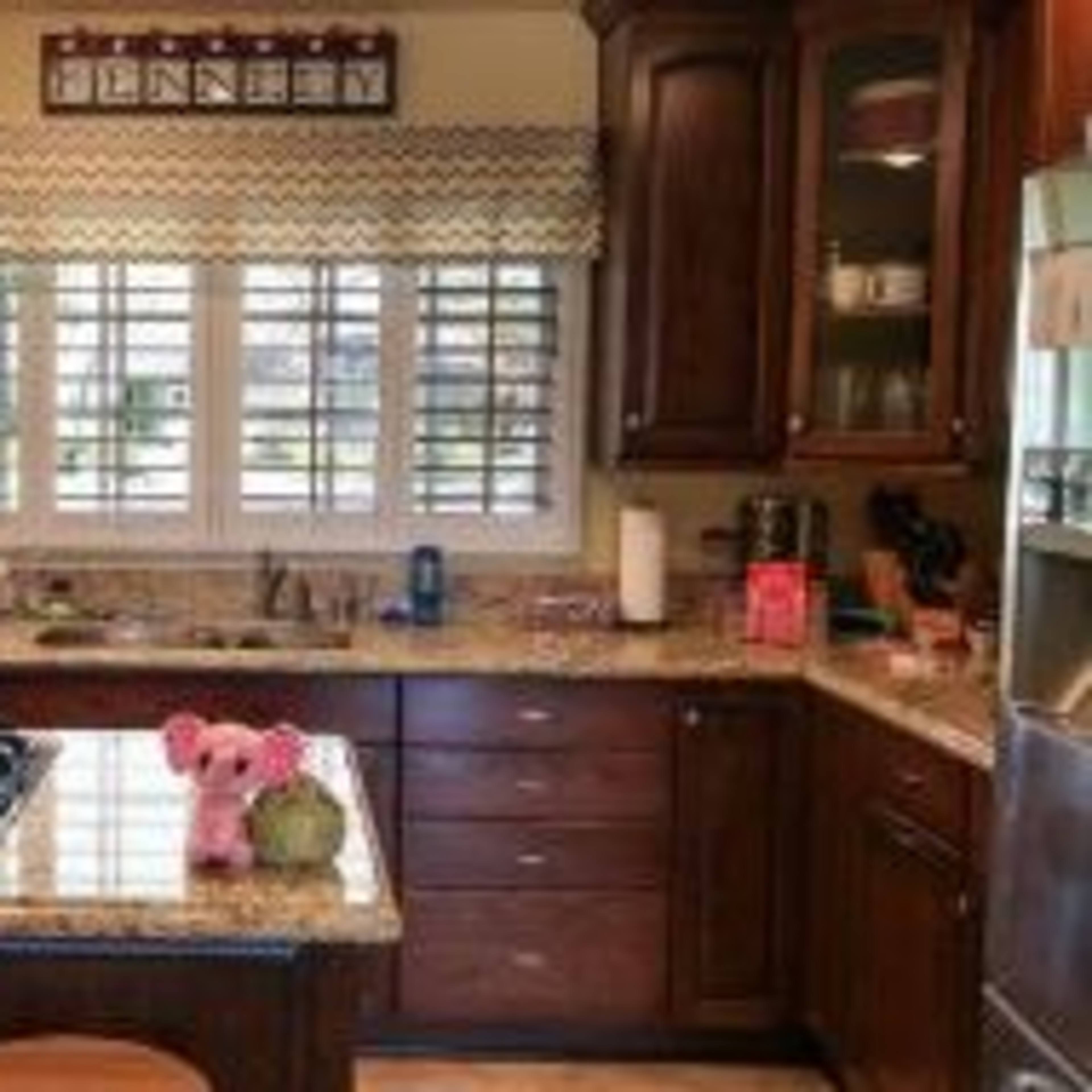 A well-organized kitchen with dark wooden cabinets, a granite countertop, and a stove on a central island.