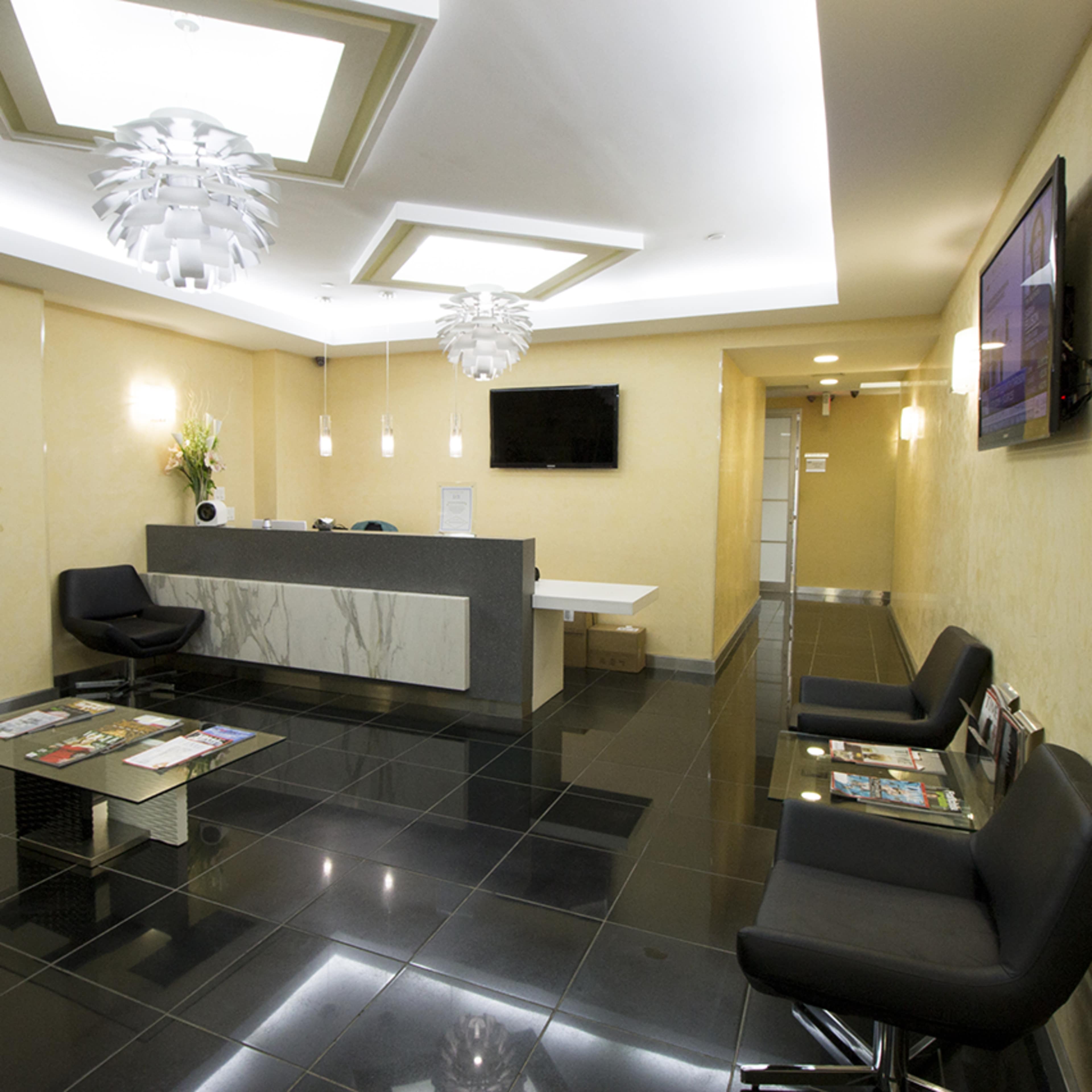 A modern reception area with black tiled flooring, a marble counter, glass partitions, and contemporary seating arrangements.