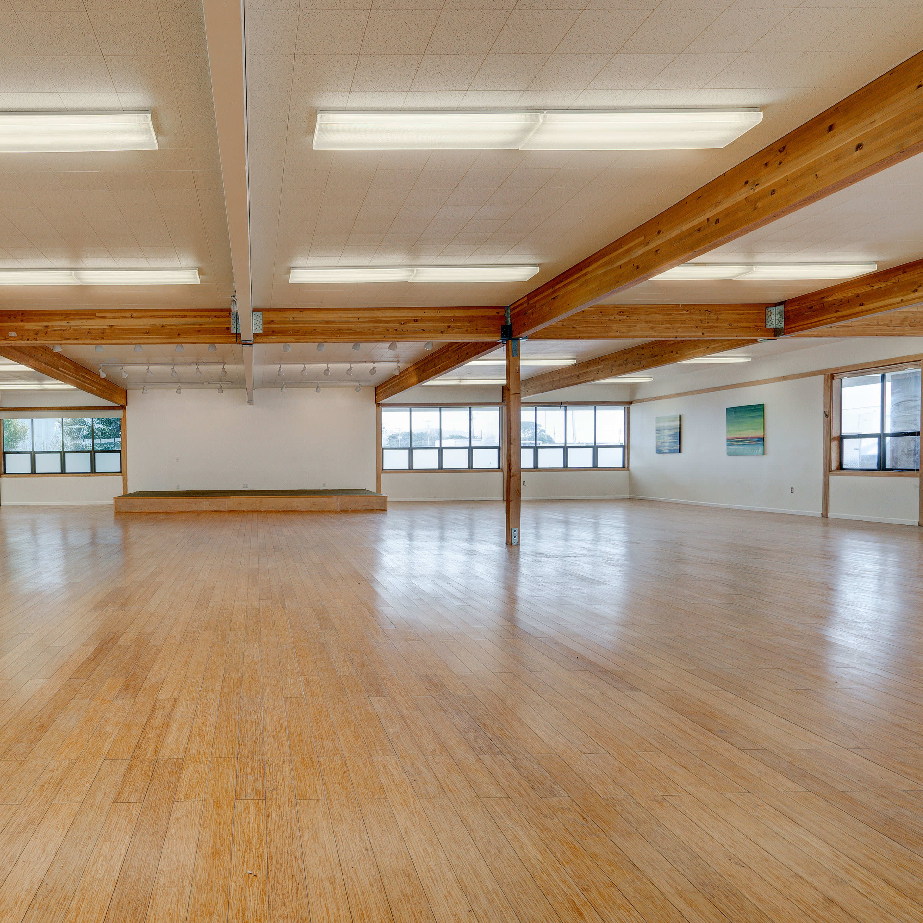 A spacious, empty dance studio with wooden beams and large windows.