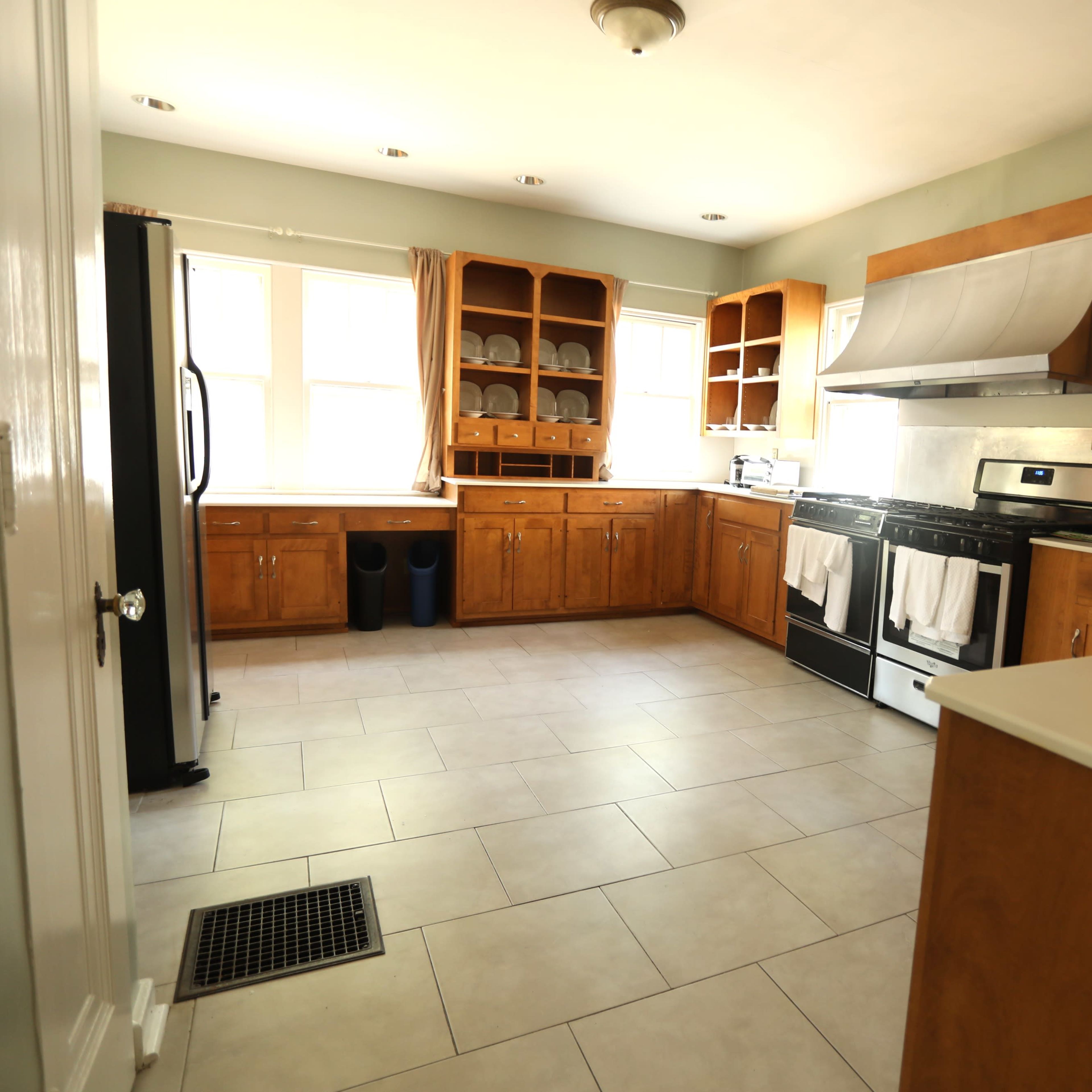 The kitchen features wooden cabinets, a stainless steel stove, a black refrigerator, and tile flooring.