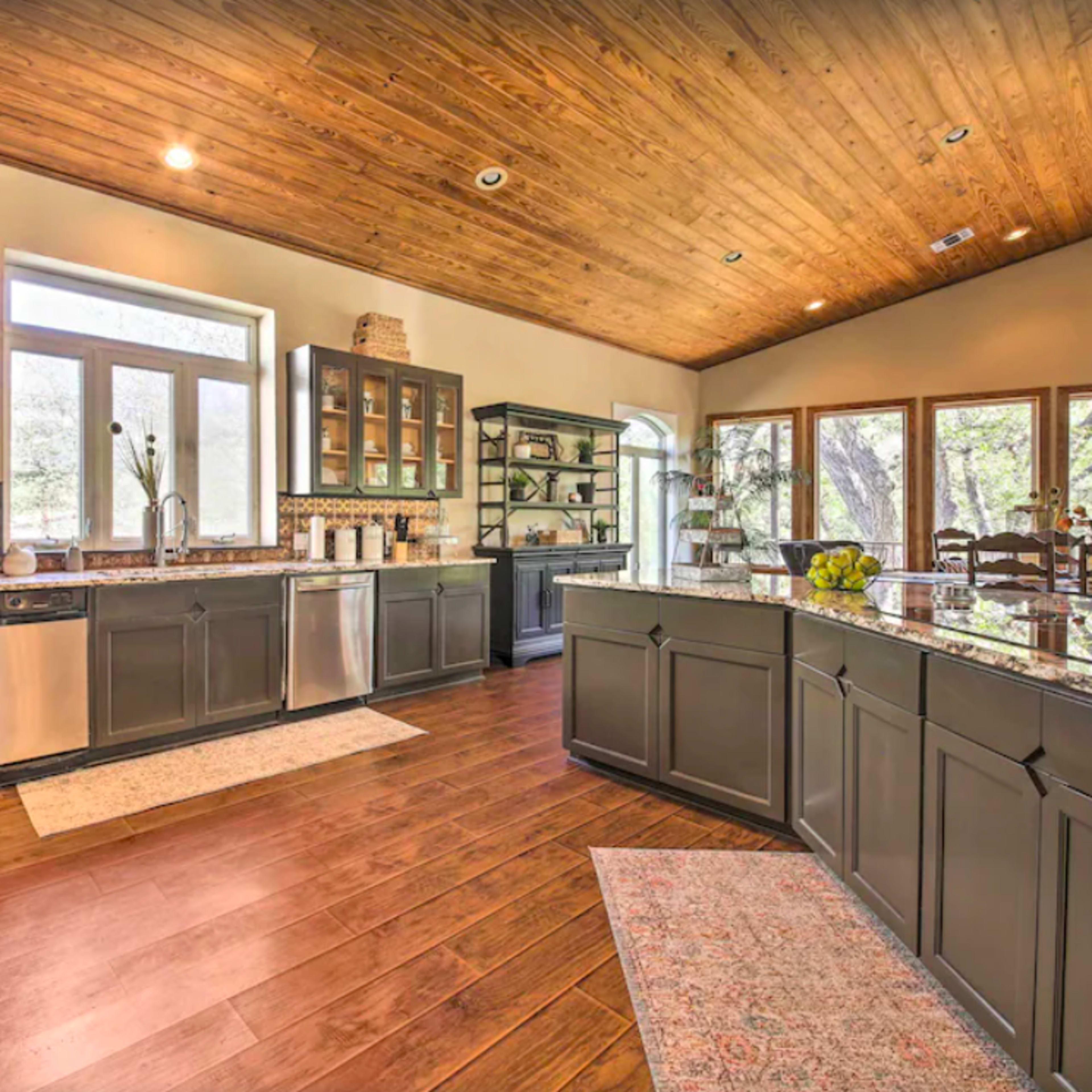 A spacious kitchen with dark cabinets, stainless steel appliances, and large windows that provide natural light.