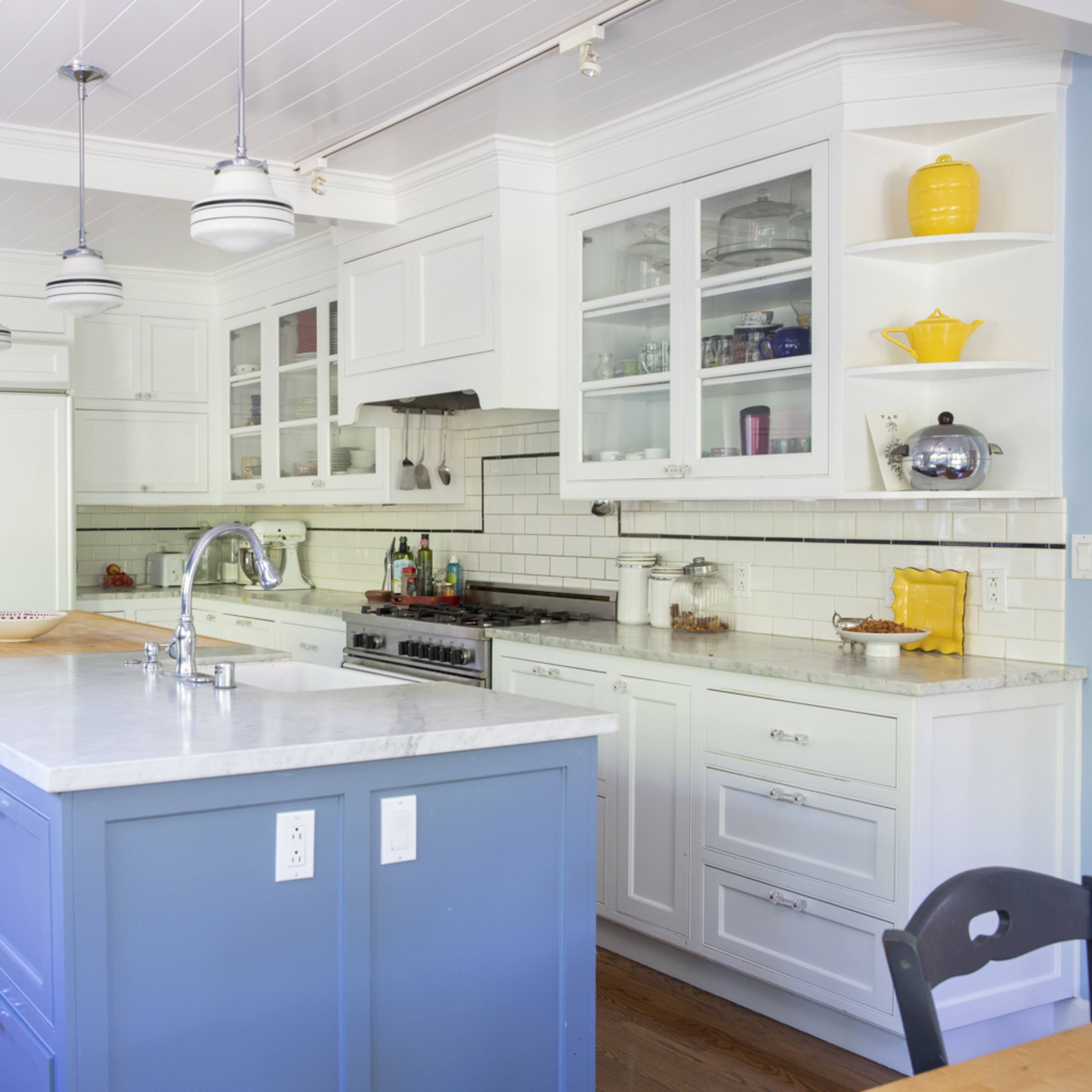 A modern kitchen with a central island, white cabinetry, and blue accent walls.