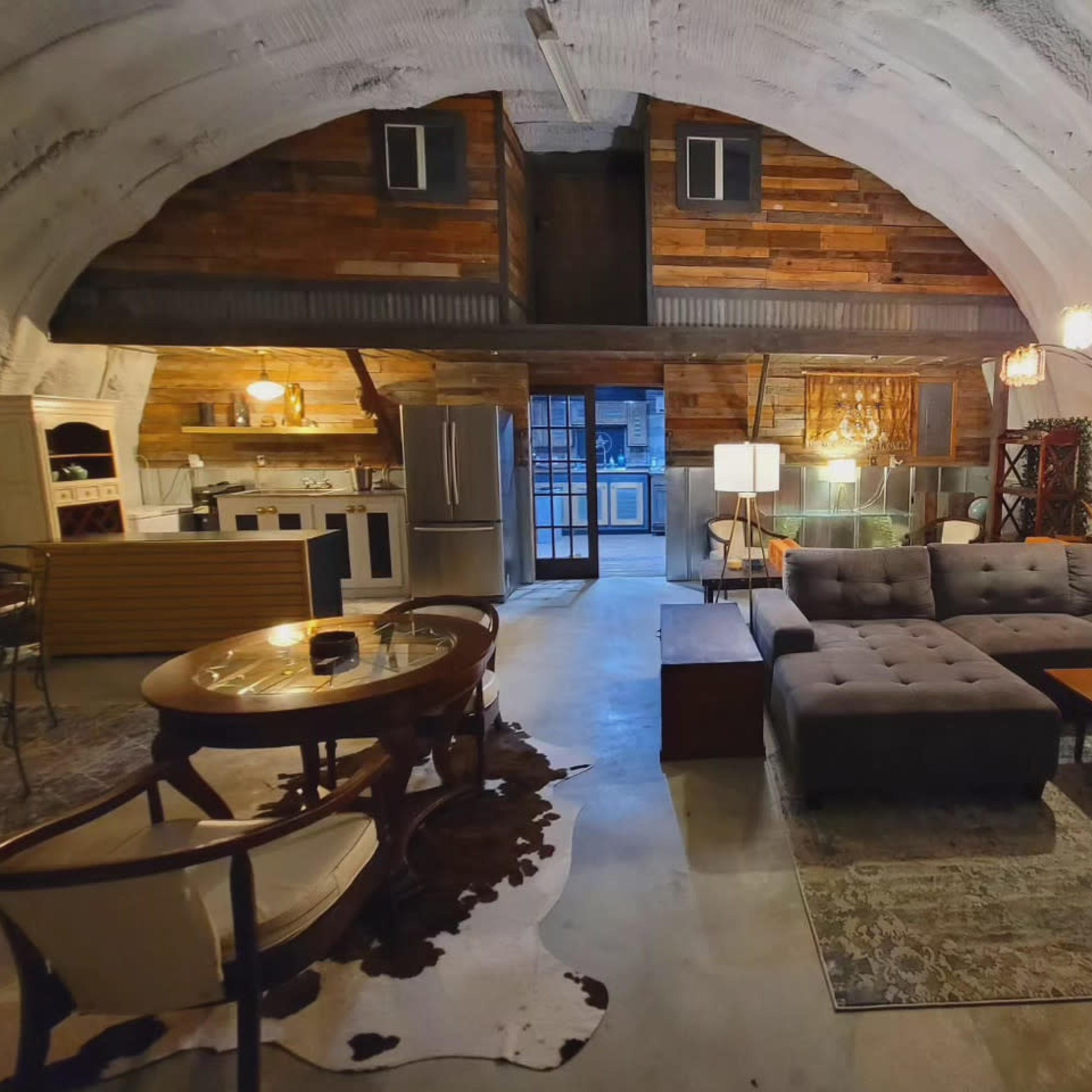 A spacious, modern living area with an arched ceiling, featuring a kitchen, dining area, and a sectional sofa.