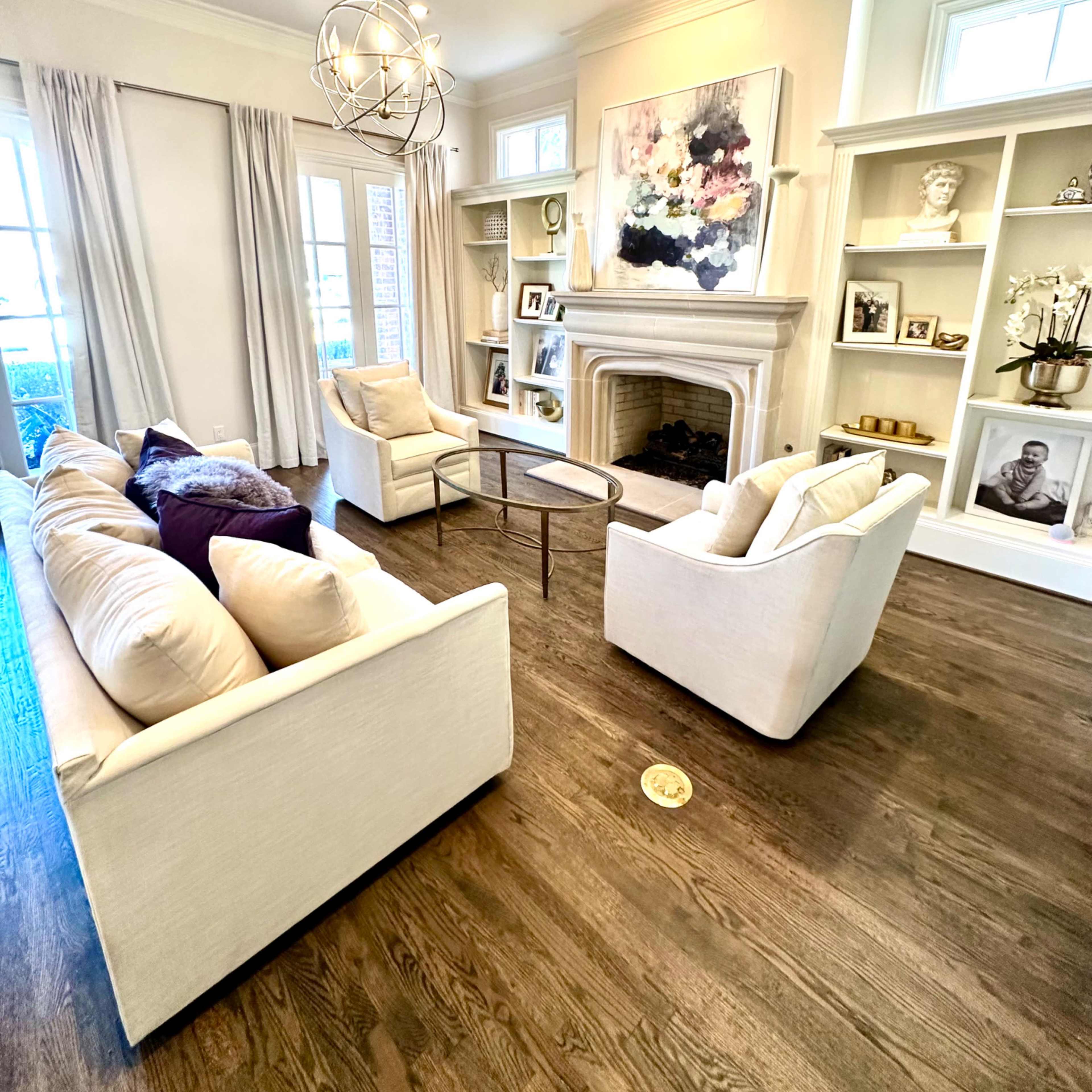 A living room featuring a light-colored sofa set arranged around a small coffee table, with built-in shelves displaying decorative items and artwork.