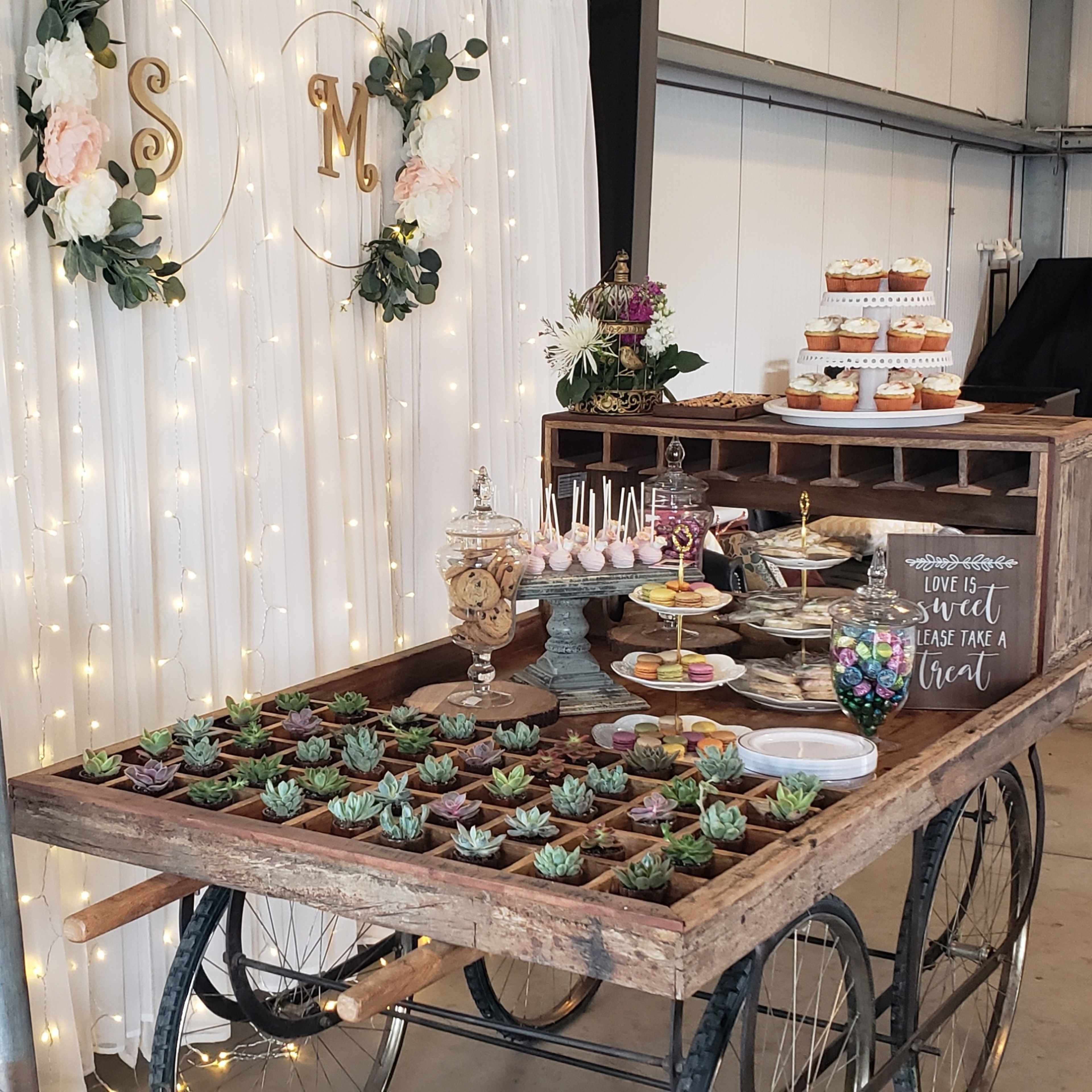 A dessert table adorned with various treats and a welcome sign for a bridal shower is set against a backdrop of fairy lights and floral decorations.
