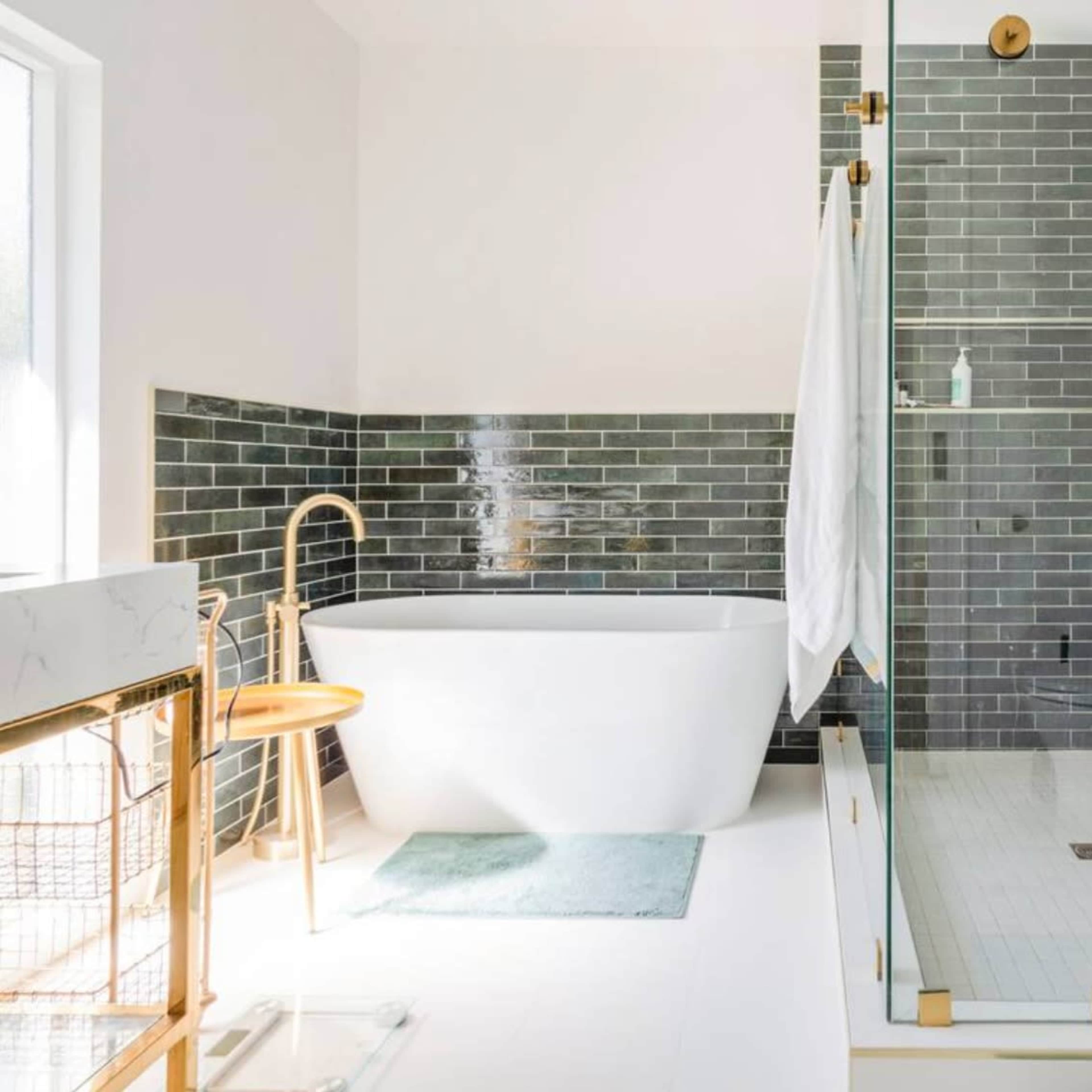 A modern bathroom features a freestanding bathtub and a glass-enclosed shower with gray tile walls.