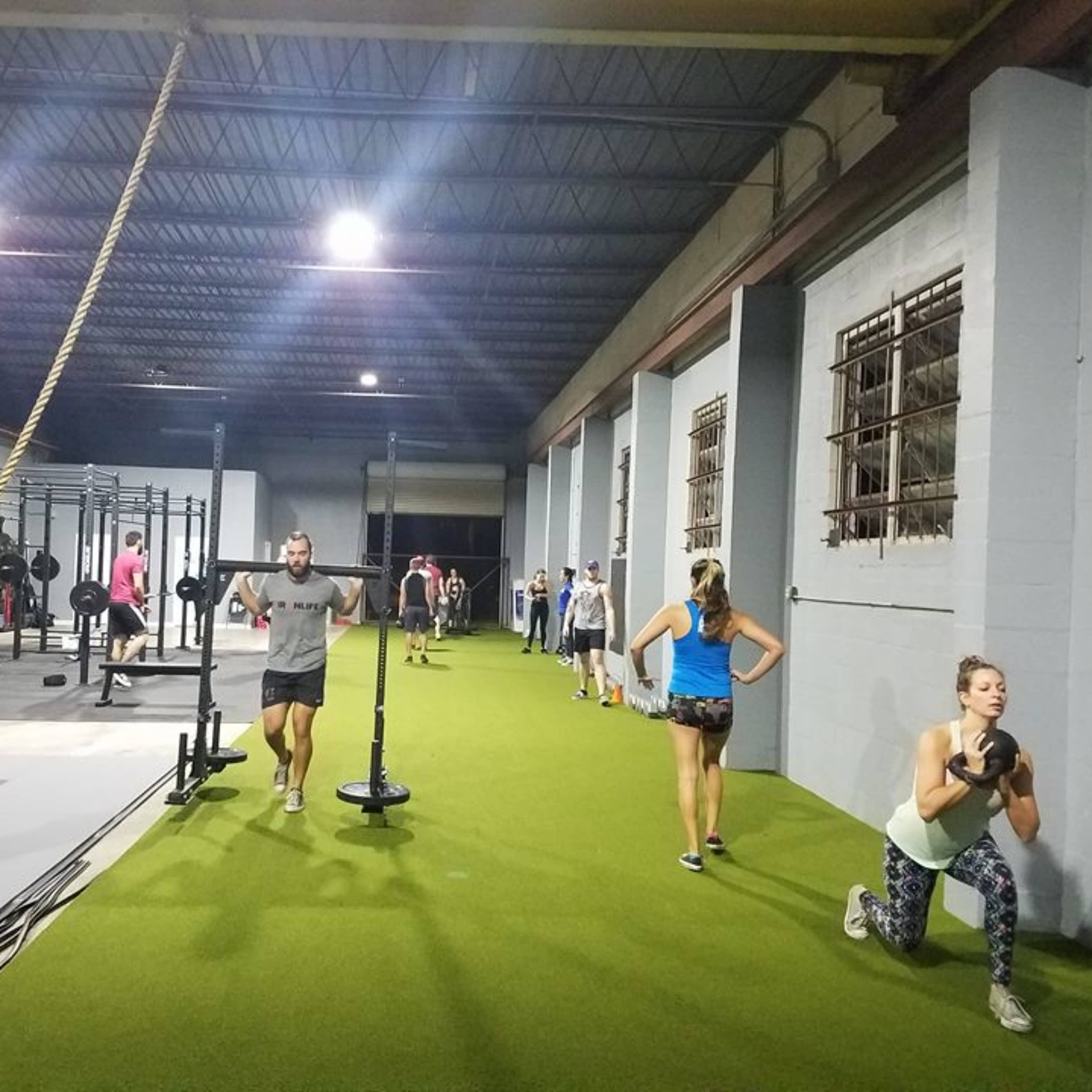 A diverse group of people is exercising in a spacious indoor gym equipped with various workout stations and fitness equipment.