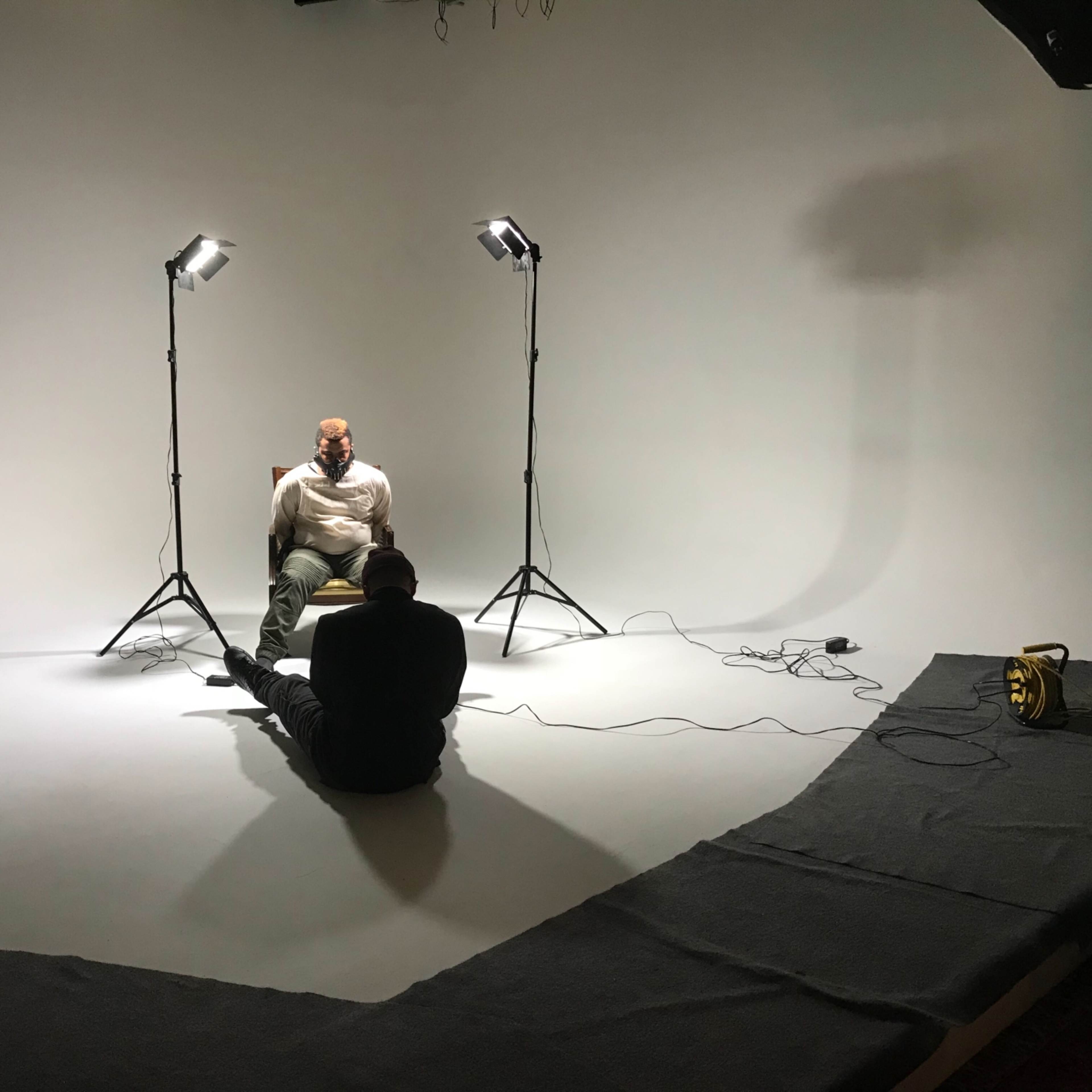 A photography studio with a green corner, white backdrop, and two softbox lights on stands.