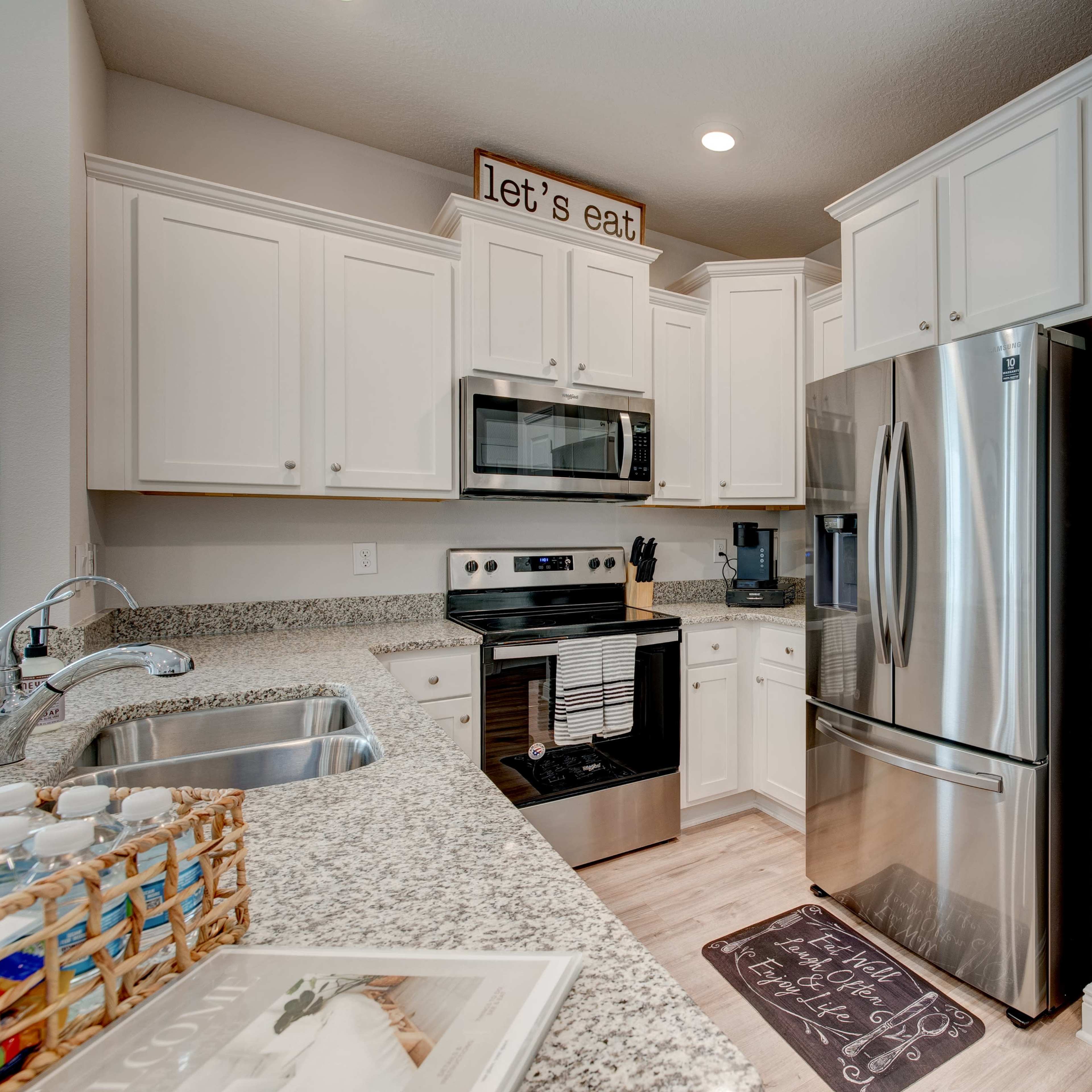 A modern kitchen with white cabinetry, stainless steel appliances, and a granite countertop.