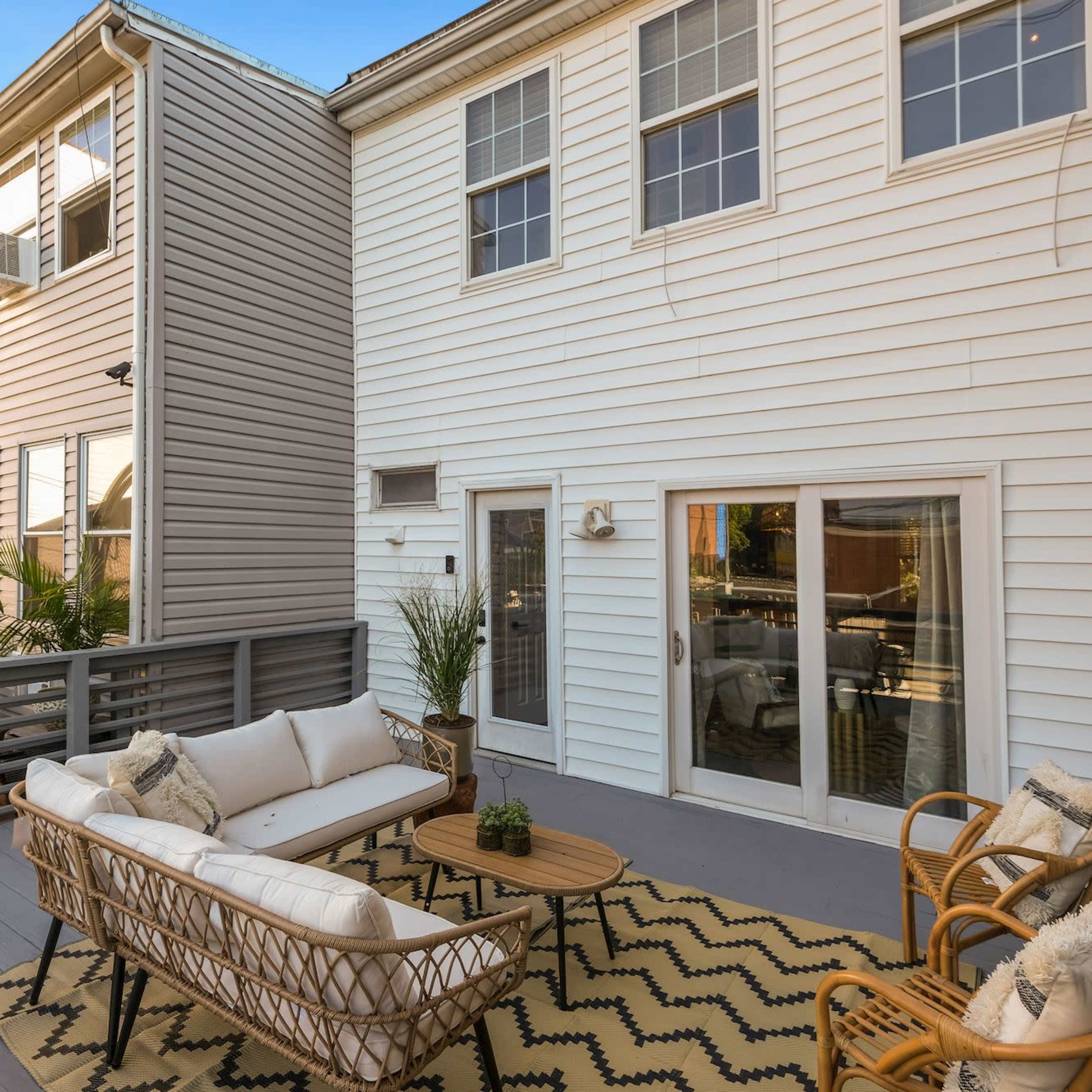 A patio area with a seating arrangement, a table, and sliding glass doors leading into a house.