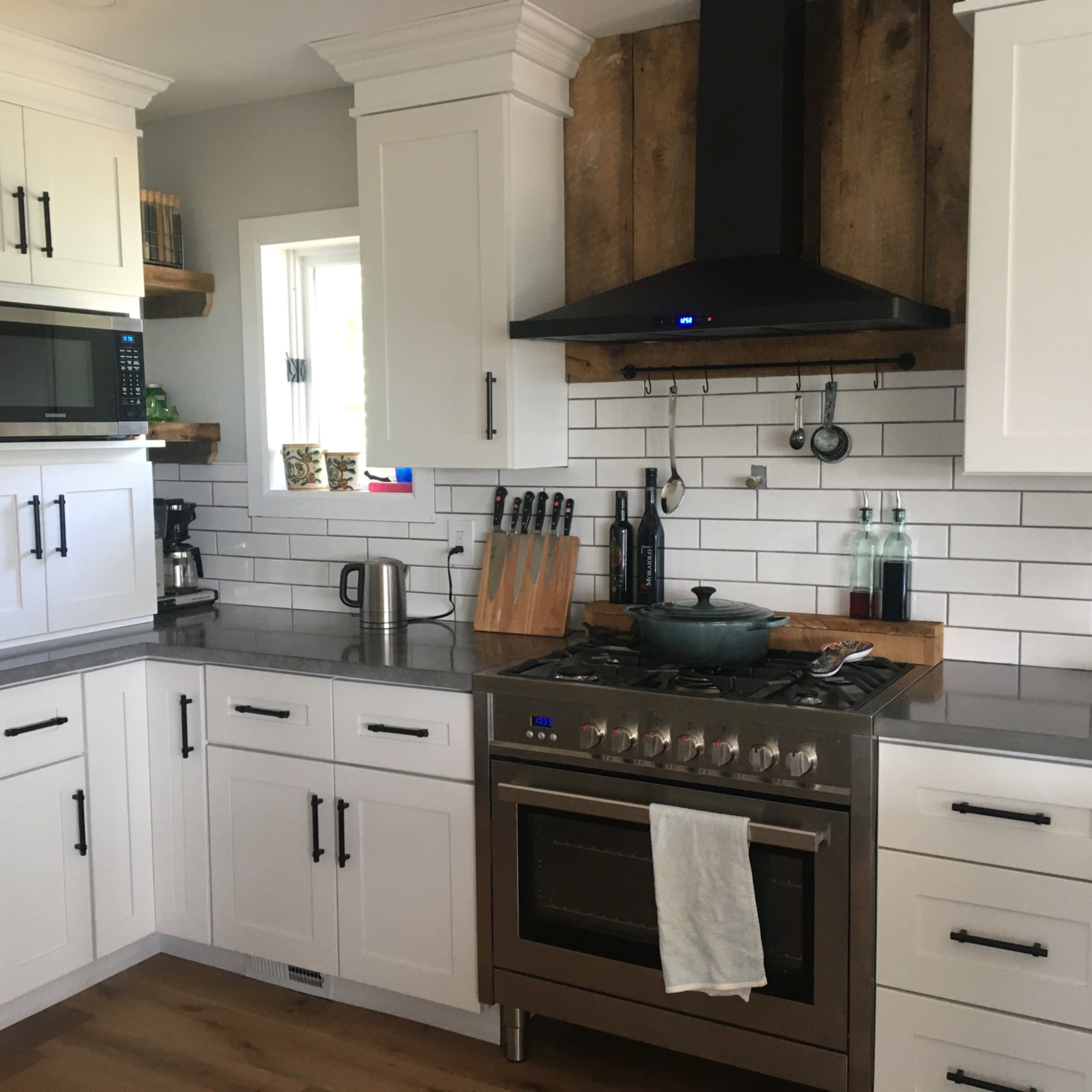 A modern kitchen featuring white cabinetry, a stainless steel stove, and a marble countertop.