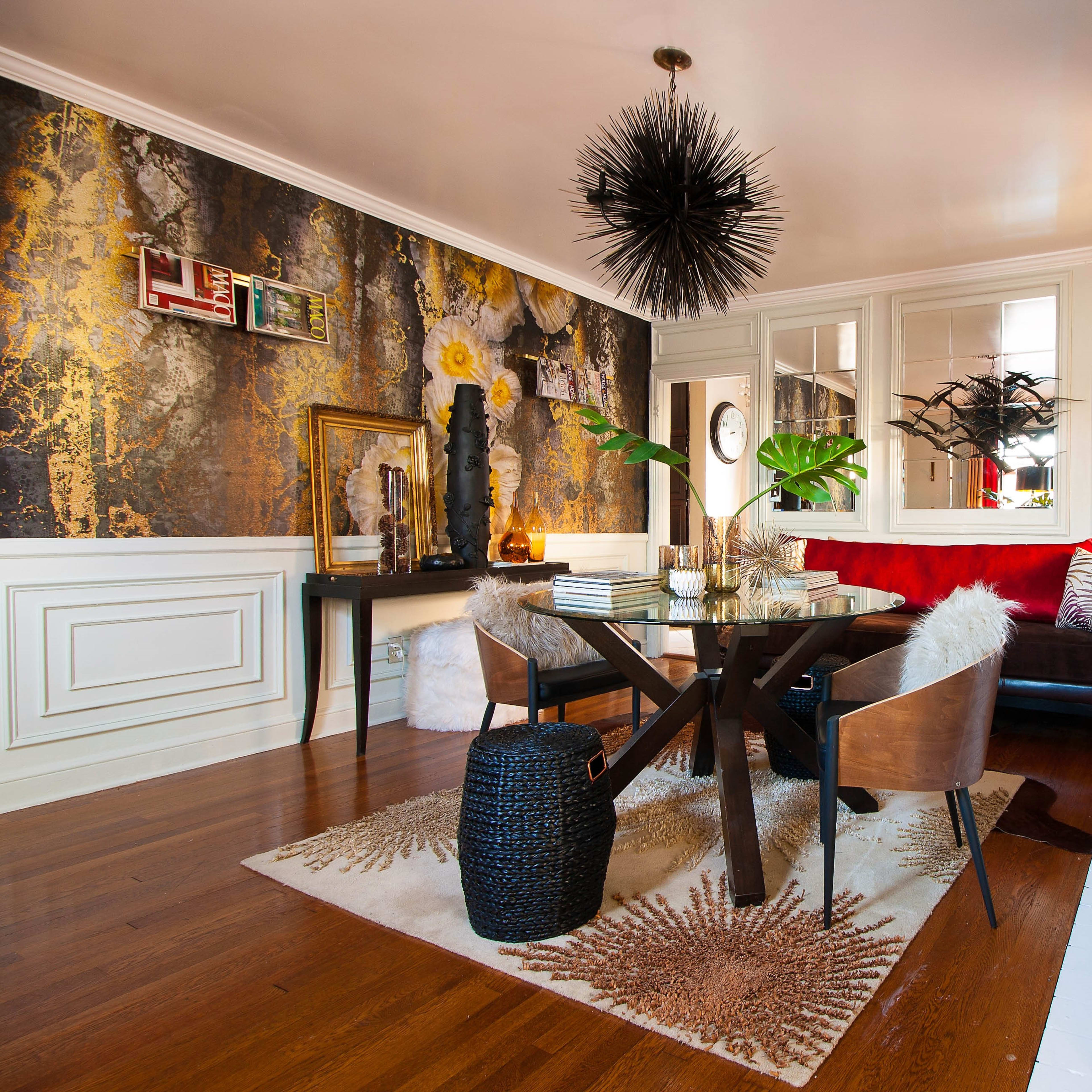 A stylish dining area with a round table, modern chairs, and decorative elements like a textured wall, a large mirror, and a fireplace.