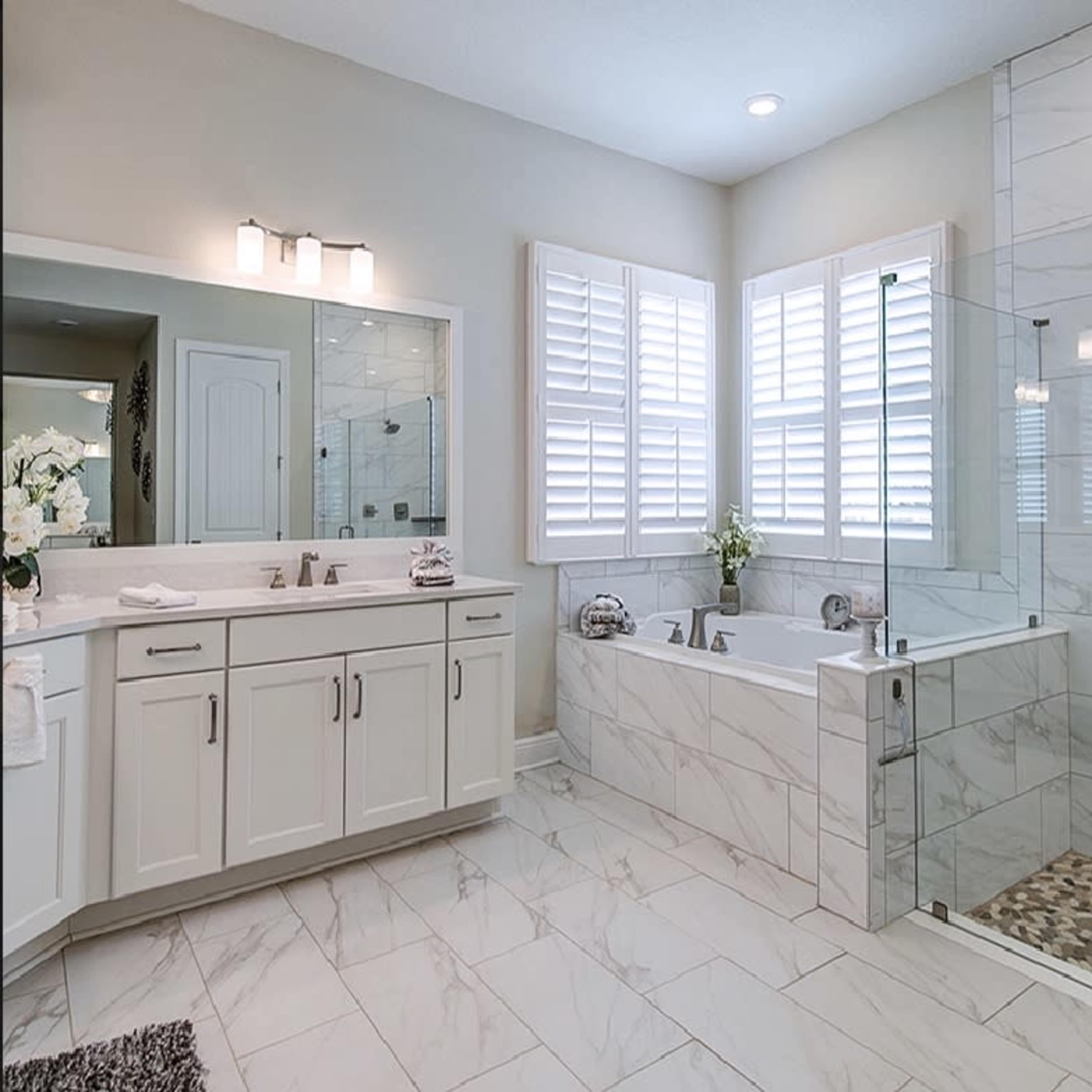 A modern bathroom featuring a freestanding tub, a glass shower enclosure, and double sinks with a large mirror.