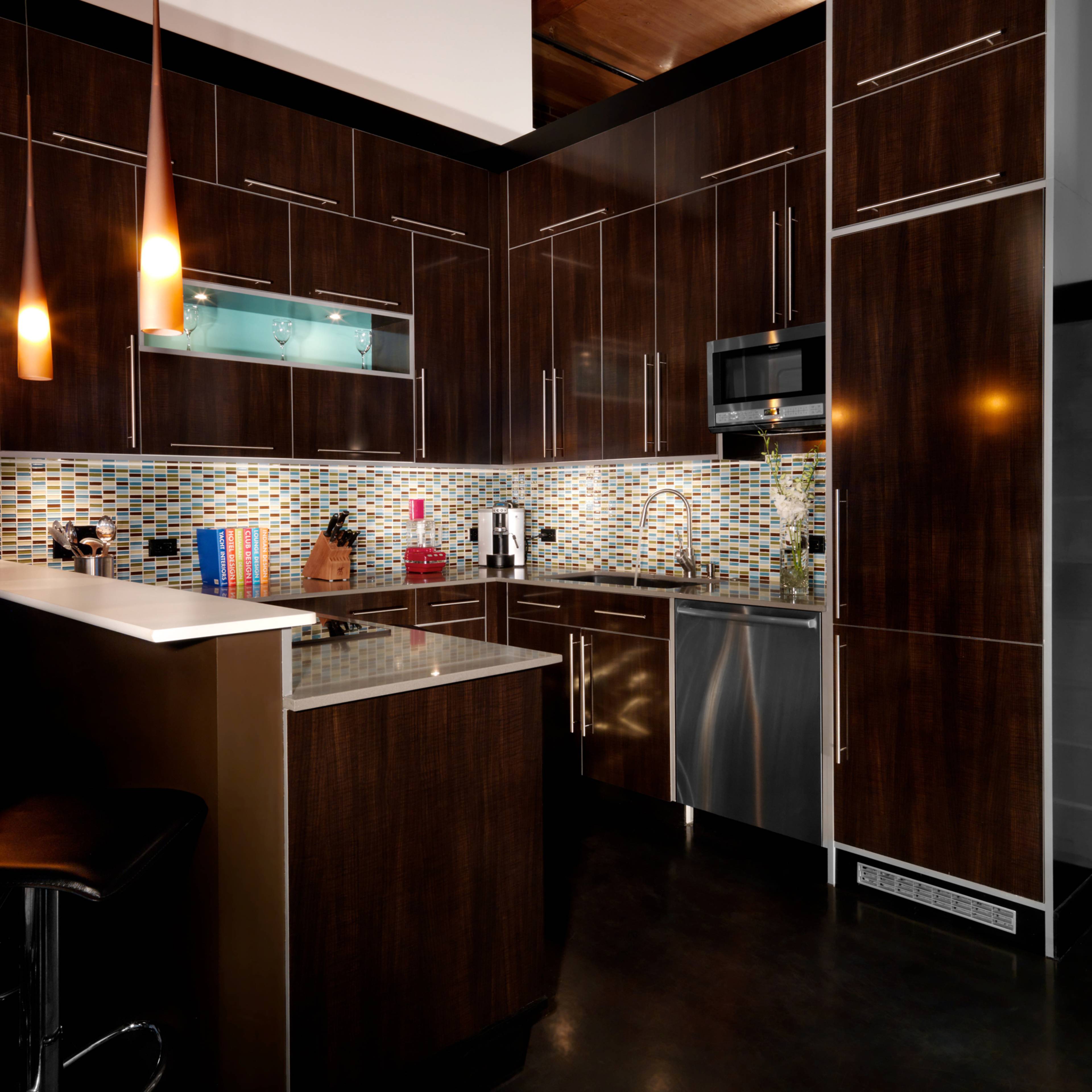 The kitchen features dark wooden cabinetry, a mosaic tile backsplash, and modern stainless steel appliances.