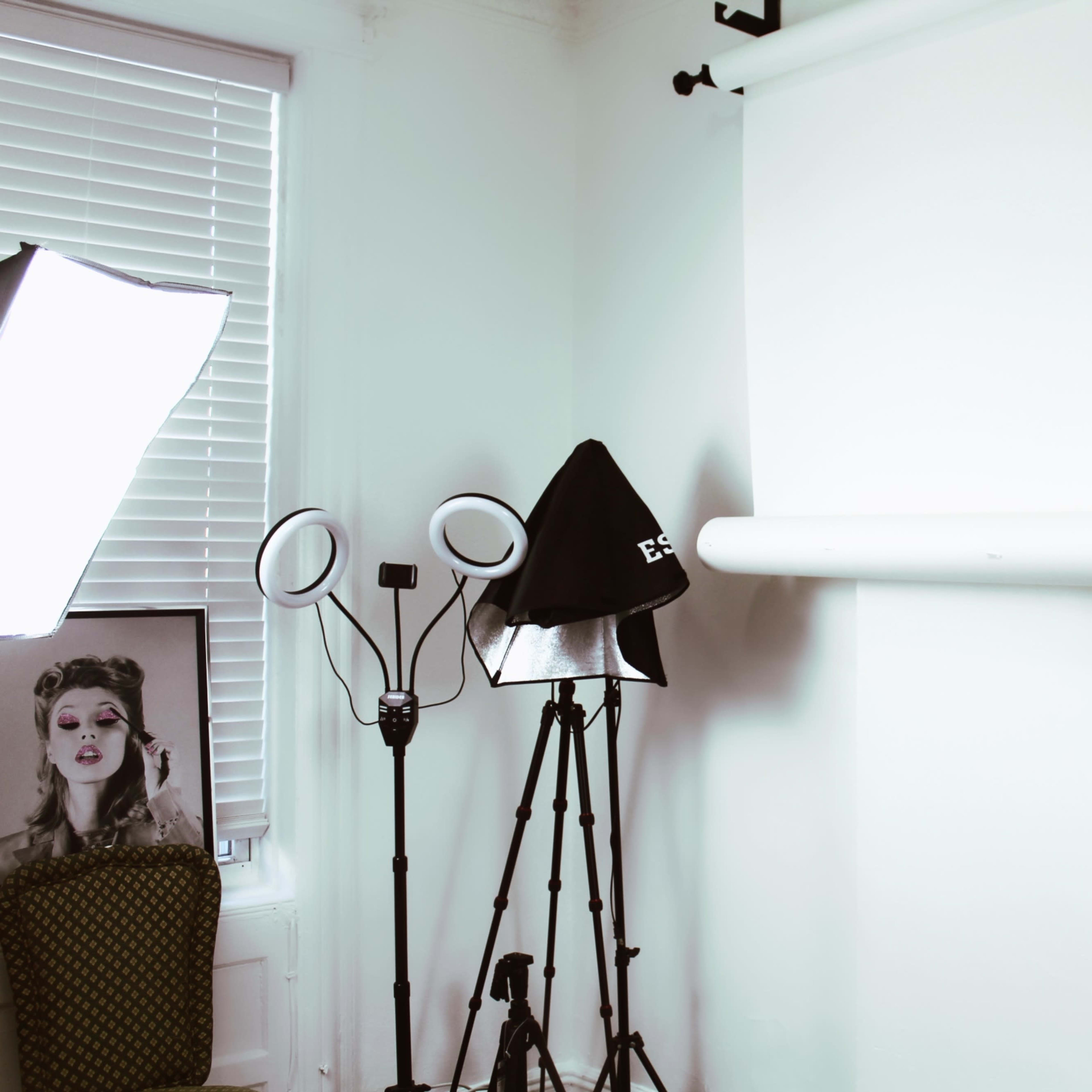 A photography studio setup with a white backdrop, lighting equipment, and a decorative chair in the corner.