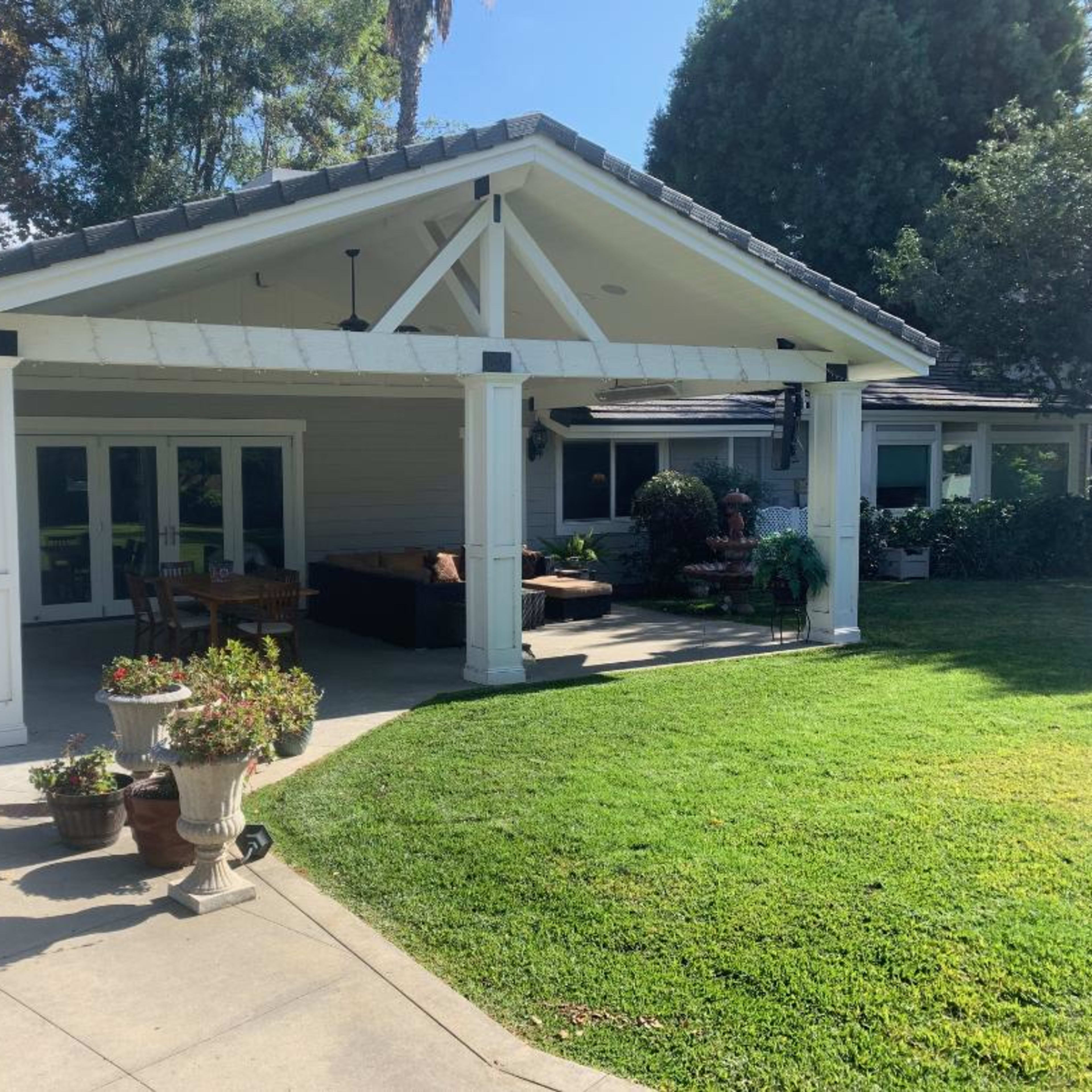 A spacious patio area connected to a single-story house, surrounded by greenery and outdoor seating.
