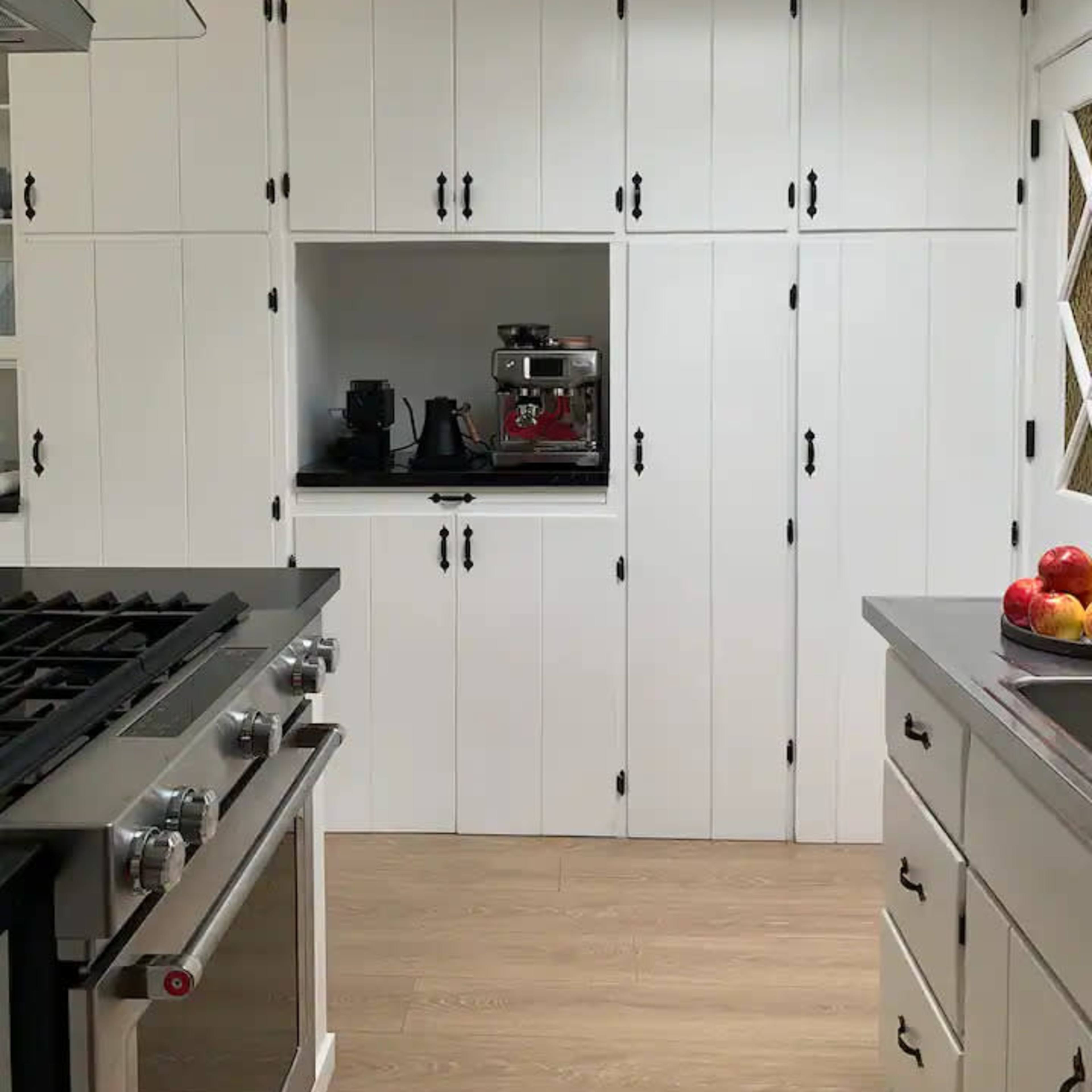 A modern kitchen with white cabinetry, a stainless steel stove, and an area designated for small appliances.
