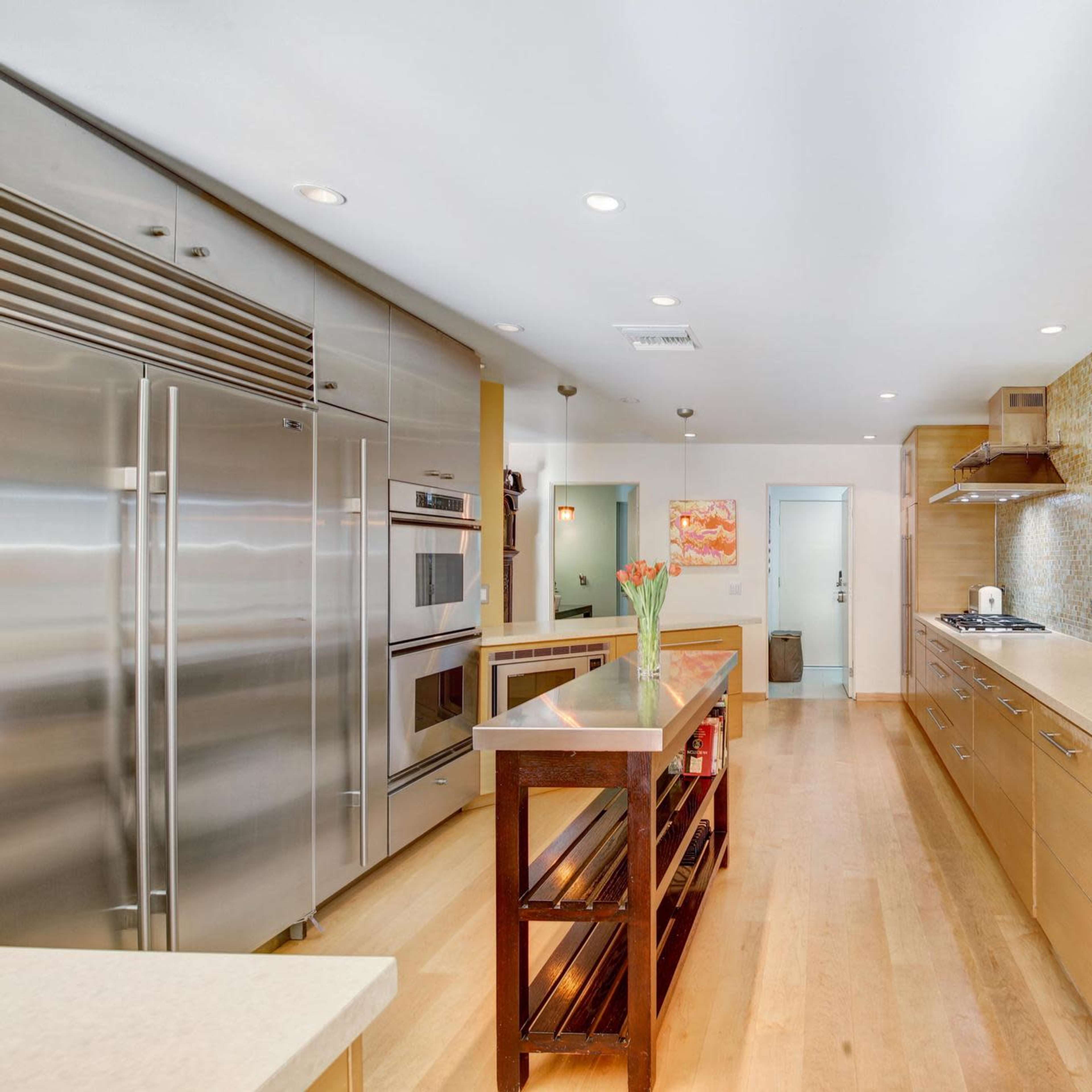 A modern kitchen with stainless steel appliances, a central island, and a mosaic tile backsplash.