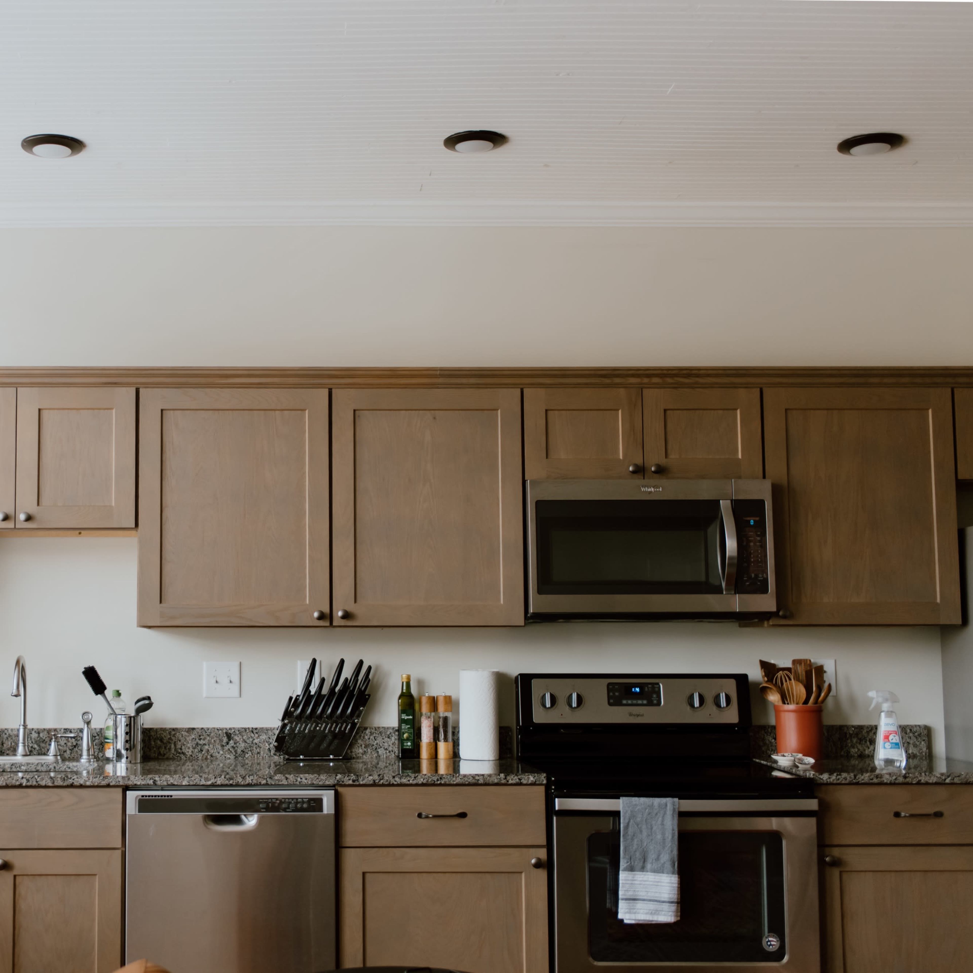 A modern kitchen with wooden cabinetry, a stainless steel microwave, and granite countertops.