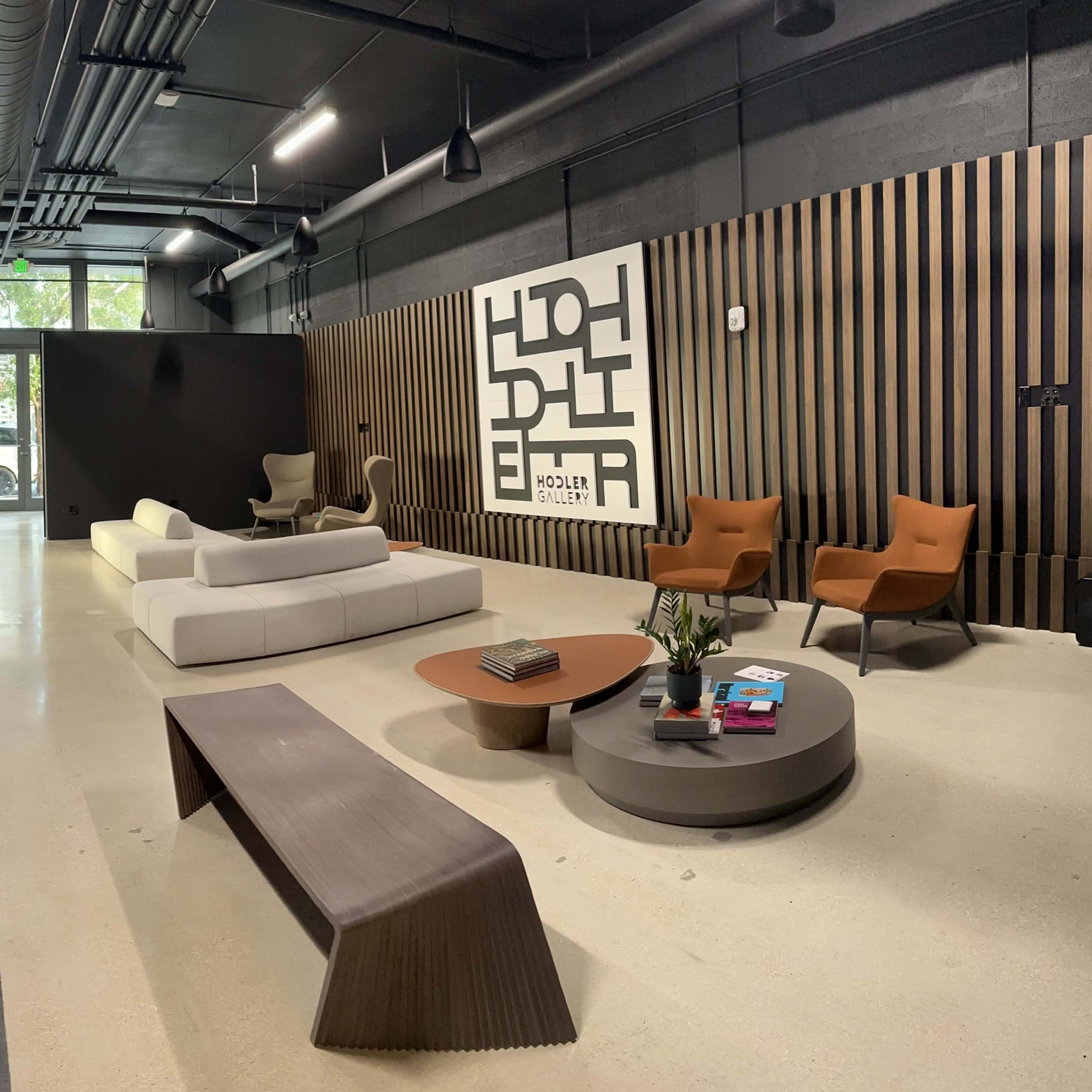 A modern interior space featuring two rows of digital displays on one side and a seating area with a coffee table and armchairs on the other.