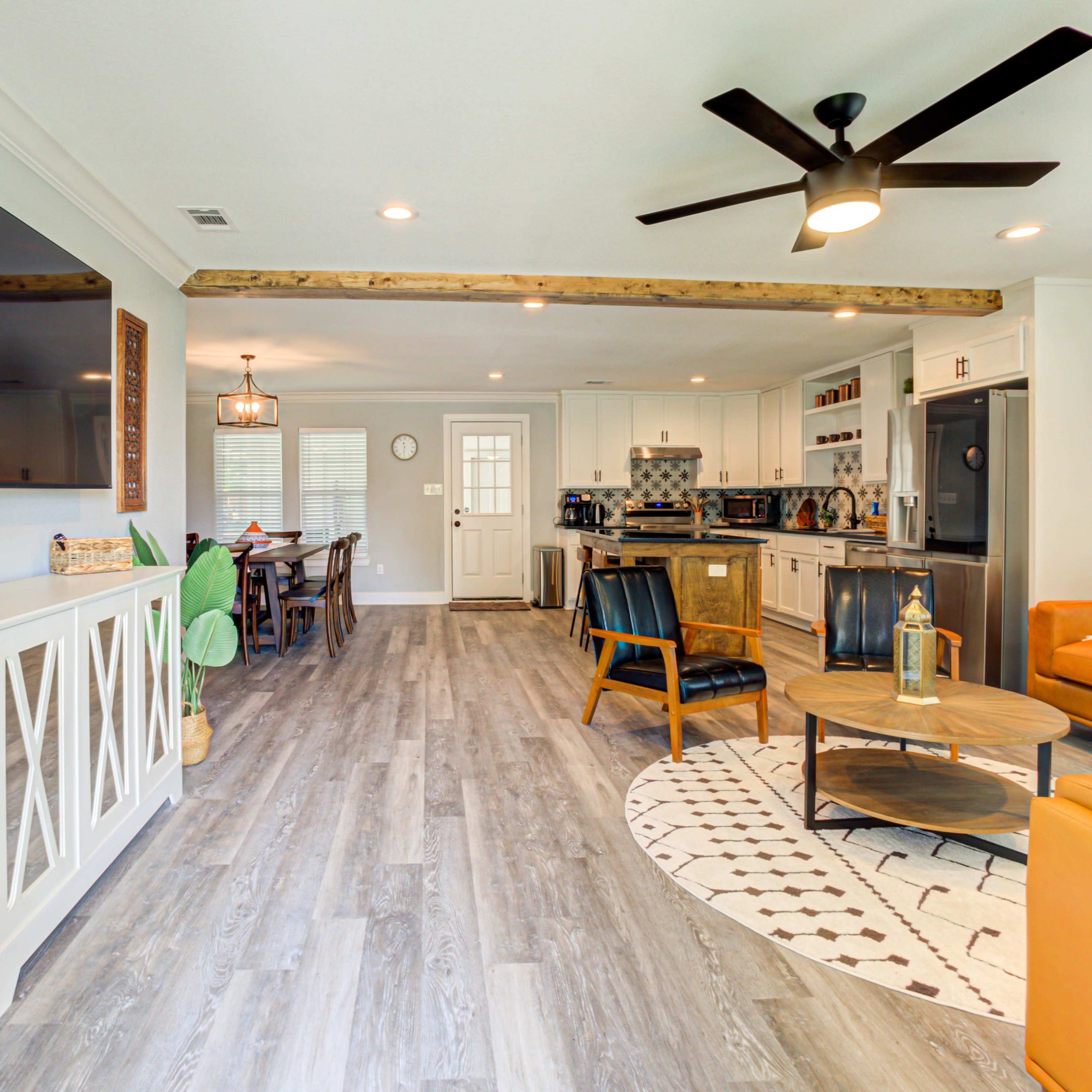A modern open-concept living space featuring a kitchen, dining area, and lounge with a mix of contemporary furnishings and wooden accents.