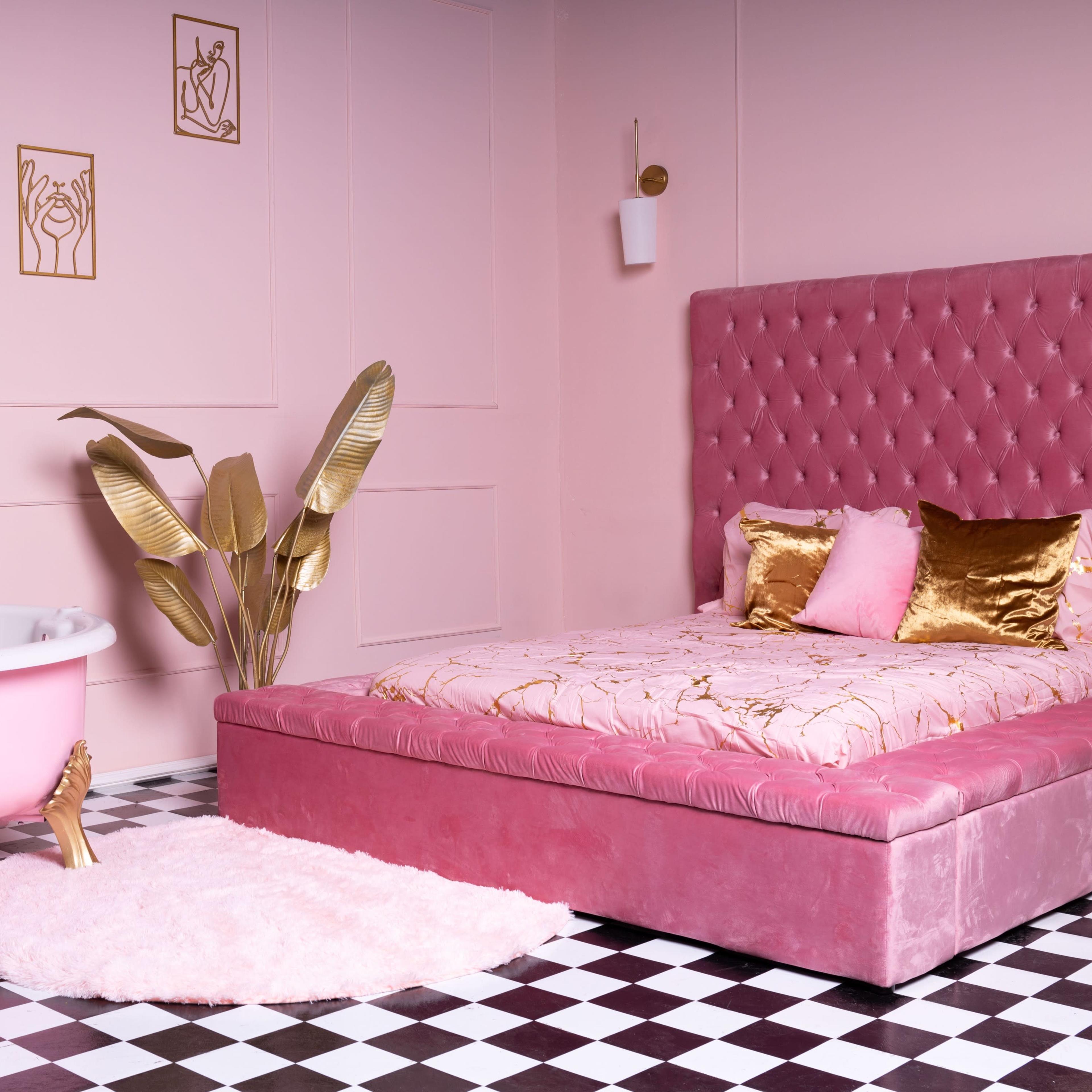 A pink bedroom with a velvet bed, a clawfoot bathtub, and decorative gold accents, set against a black and white checkered floor.