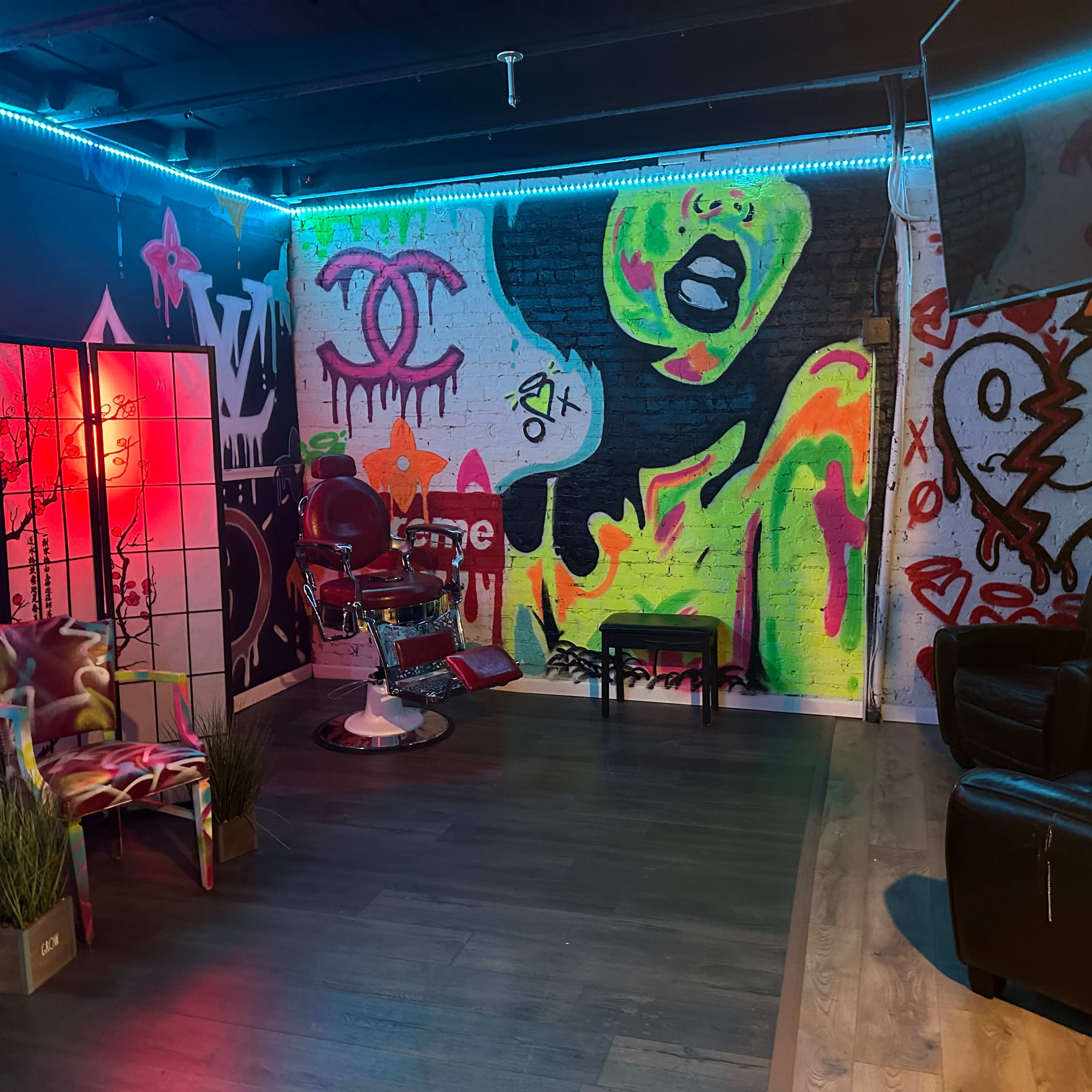 A vibrant tattoo studio with graffiti art on the walls, a tattoo chair in the center, and two chairs positioned nearby.