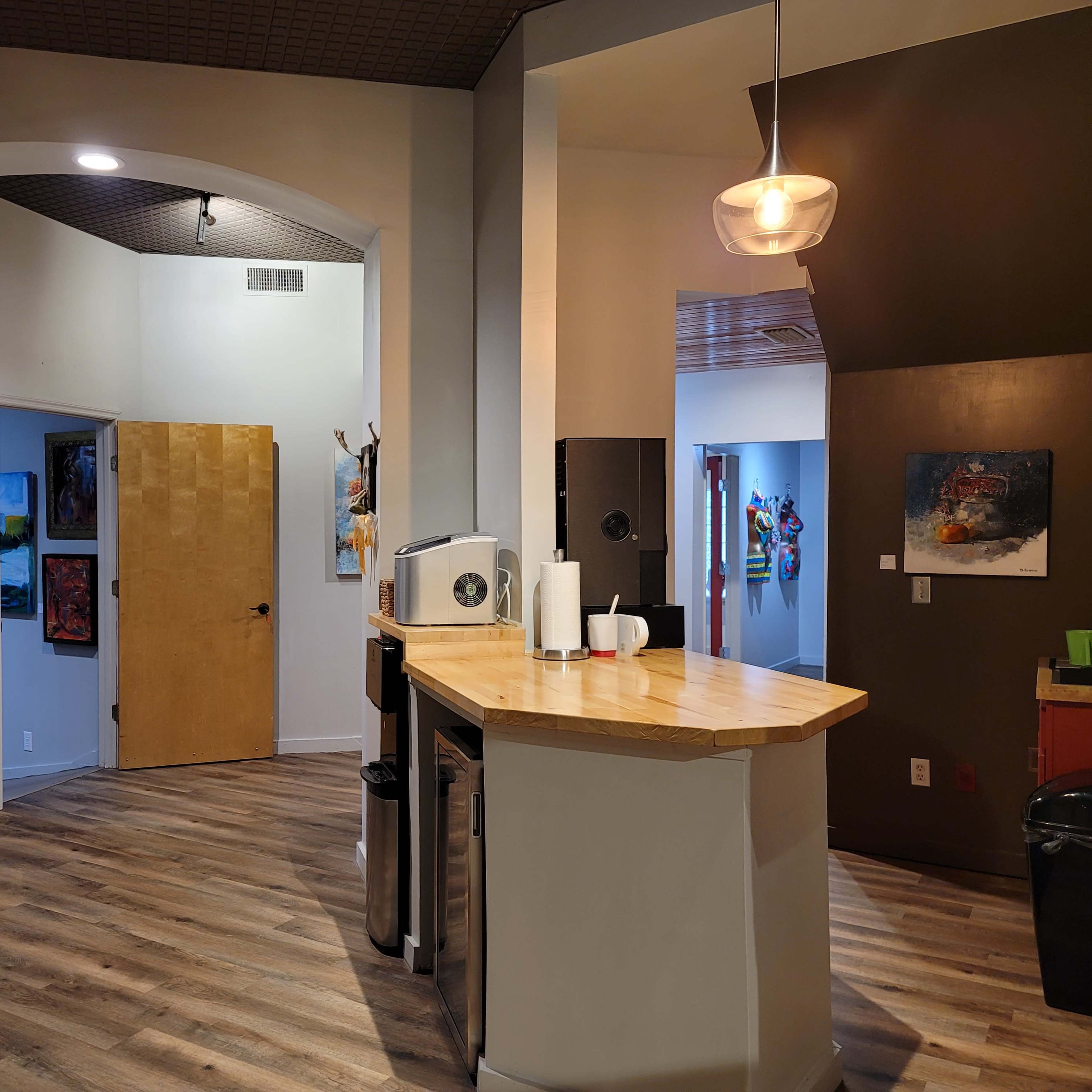 A modern interior space with a wooden countertop, appliances, and walls adorned with colorful artwork.