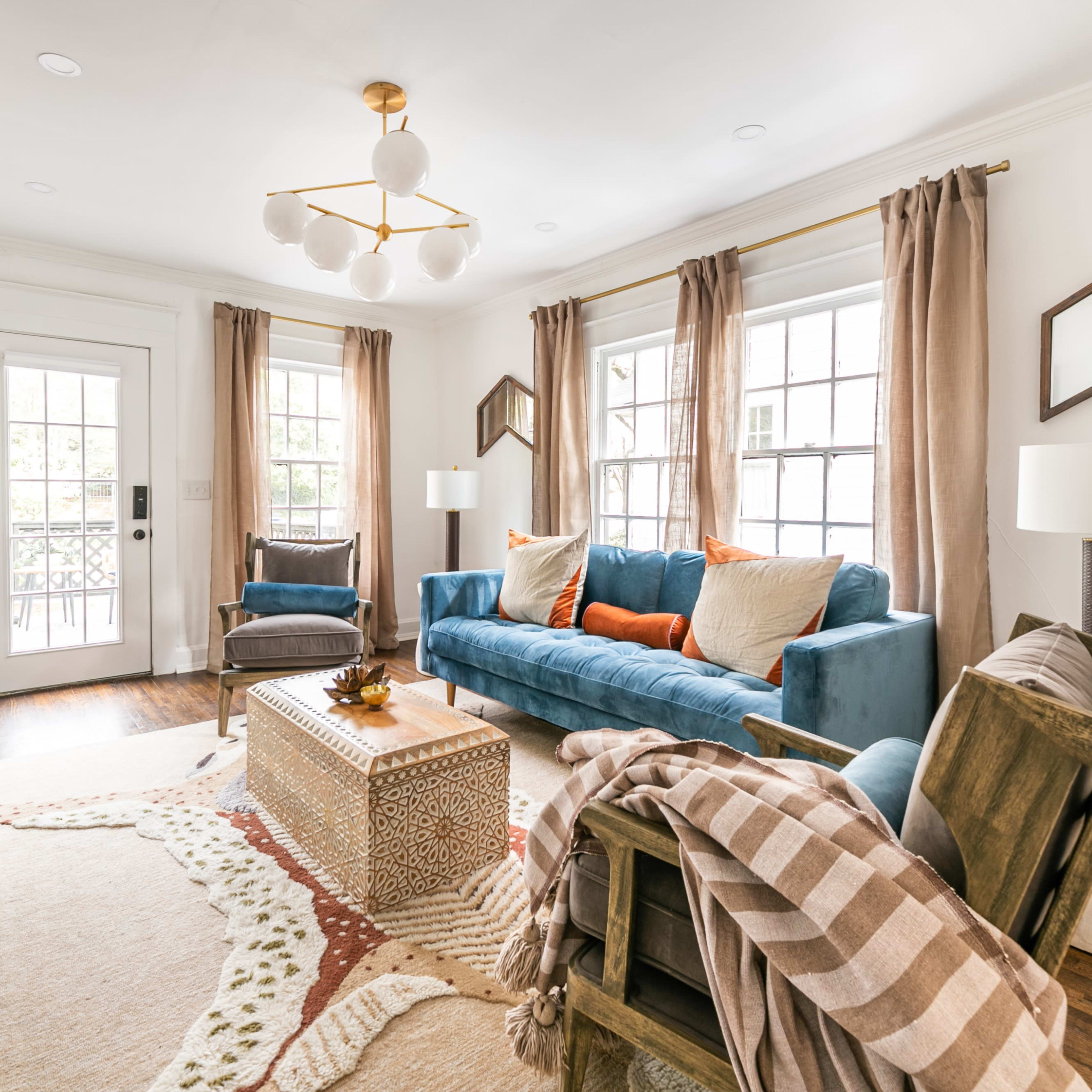 The living room features a blue sofa, two lamps, and a coffee table, set around a patterned rug and a fireplace.