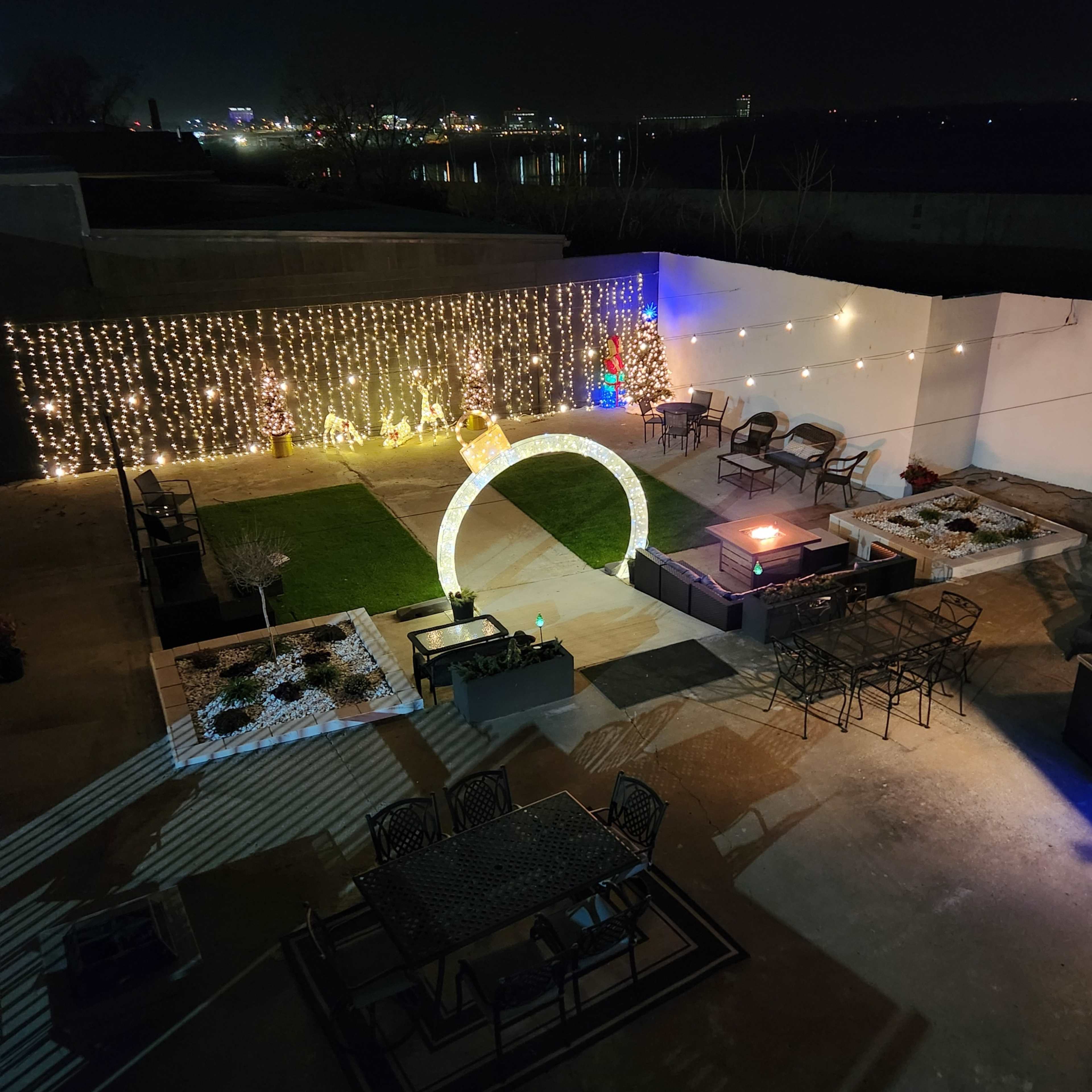 An outdoor patio area with decorative lighting, a circular arch, and seating arrangements.