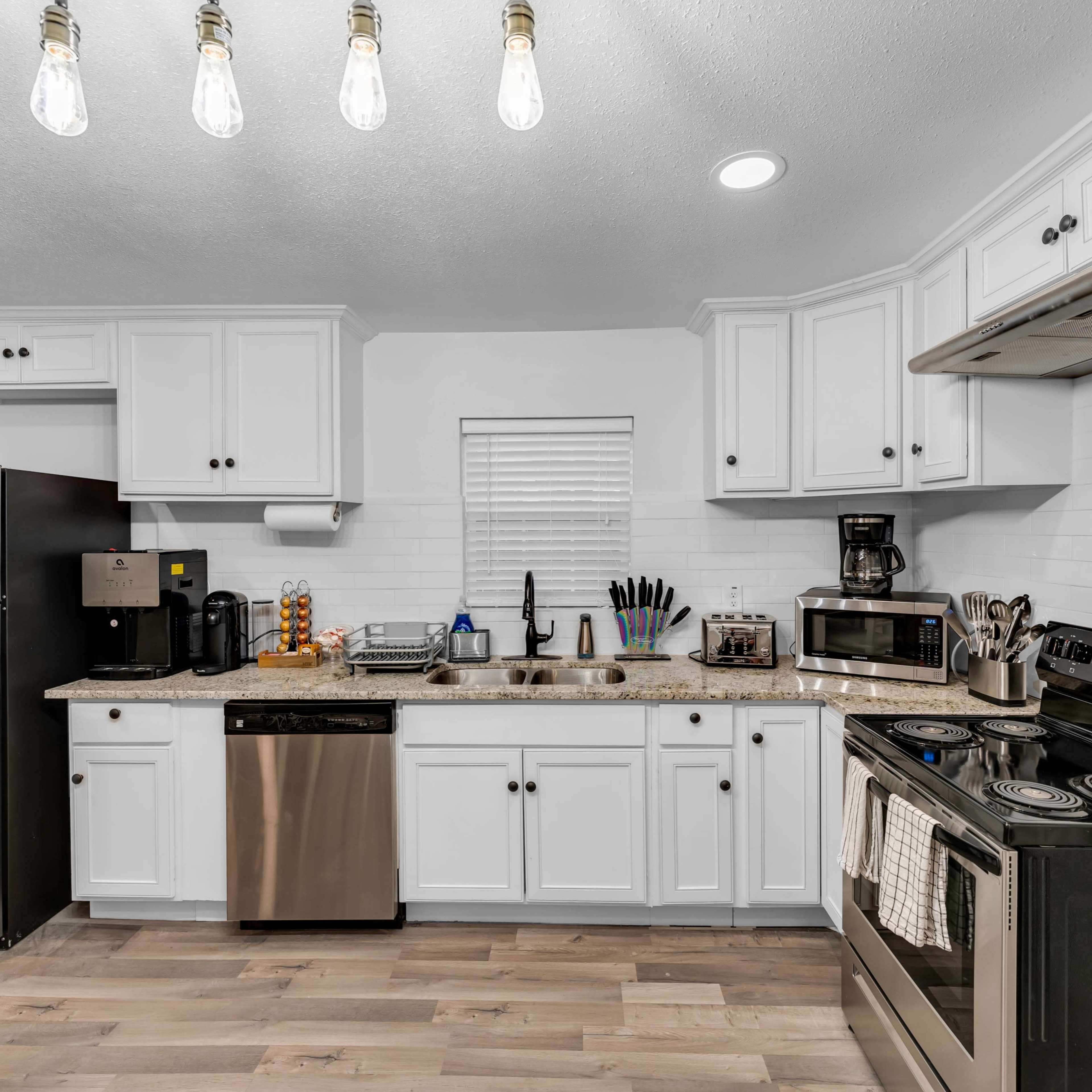 A modern kitchen with white cabinets, stainless steel appliances, and a light-colored countertop.