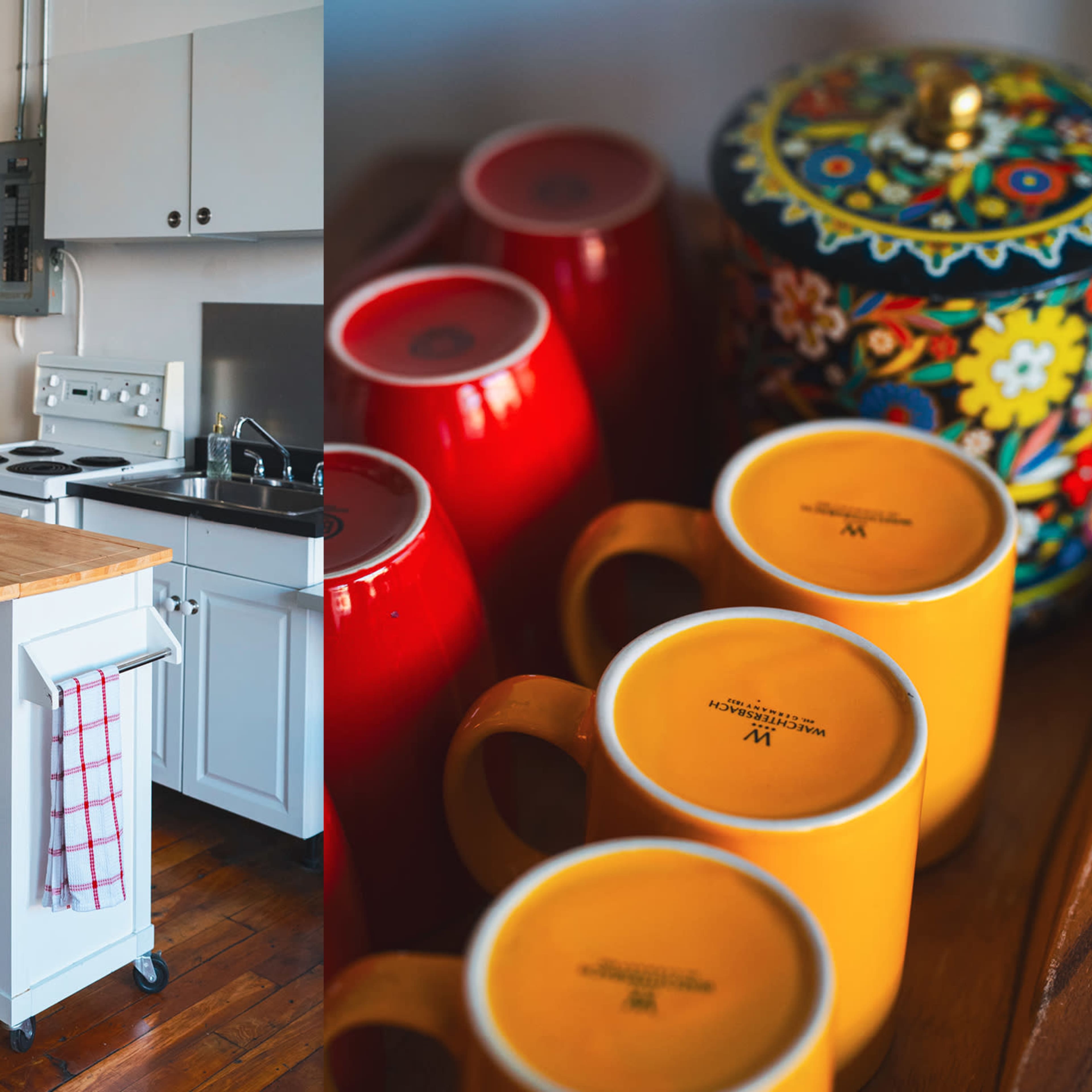 A bright kitchen with a wooden island and two stools on the left, and a collection of colorful mugs and a decorative jar on the right.