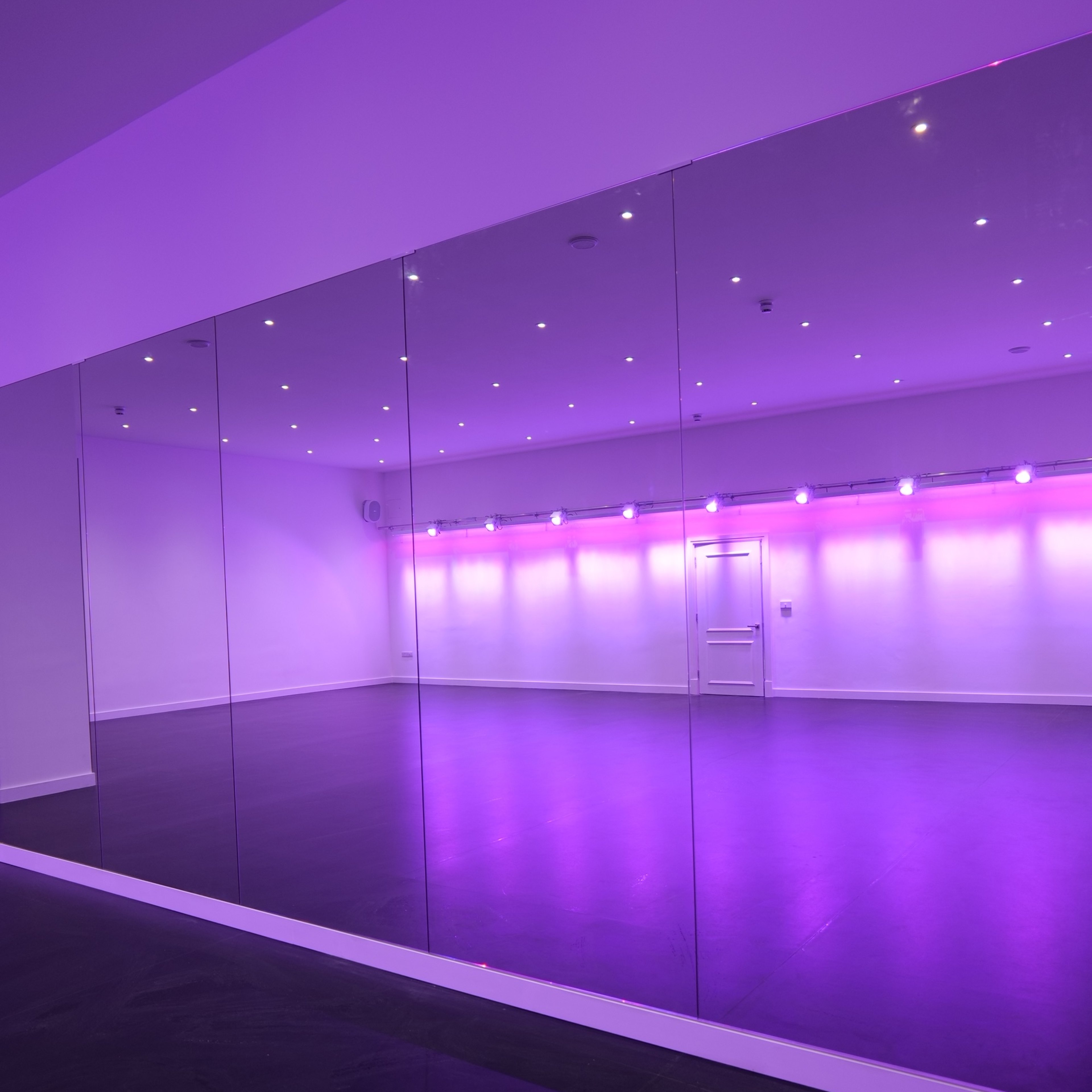 A spacious room with mirrored walls and purple ambient lighting.